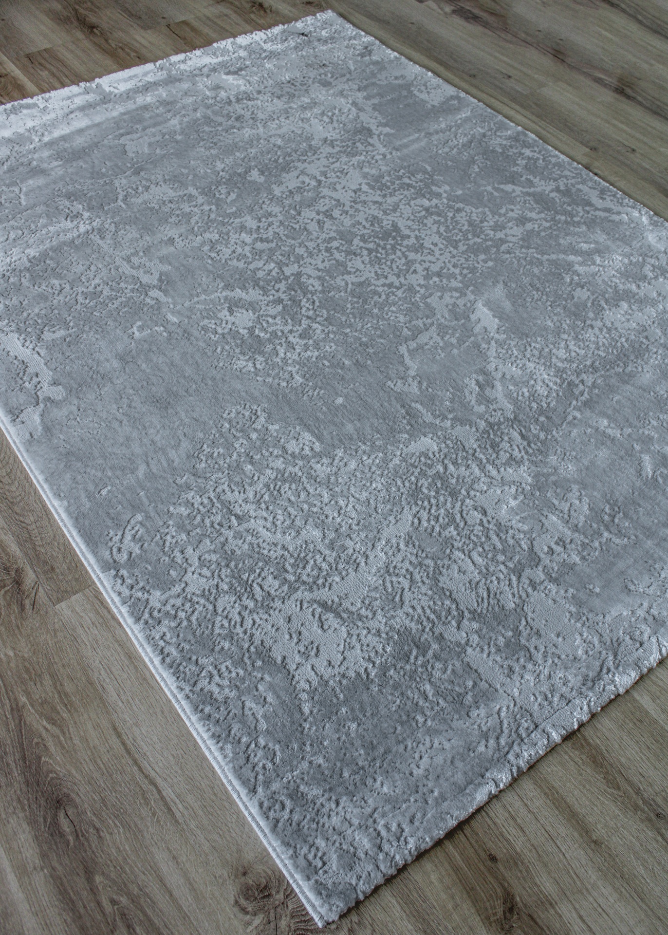 Tapete cinza texturizado sobre chão de madeira clara
