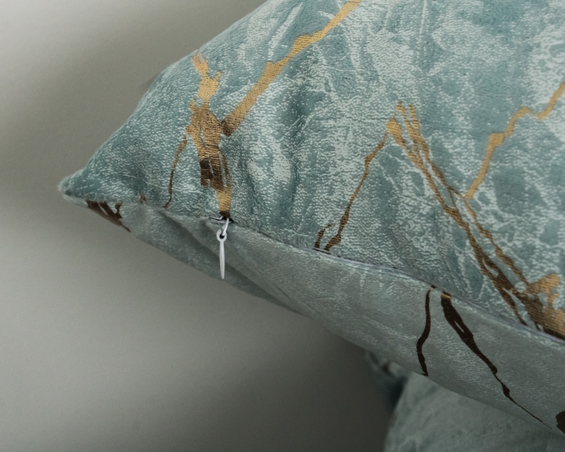 Travesseiro azul claro com padrão abstrato dourado e azul escuro e fecho branco