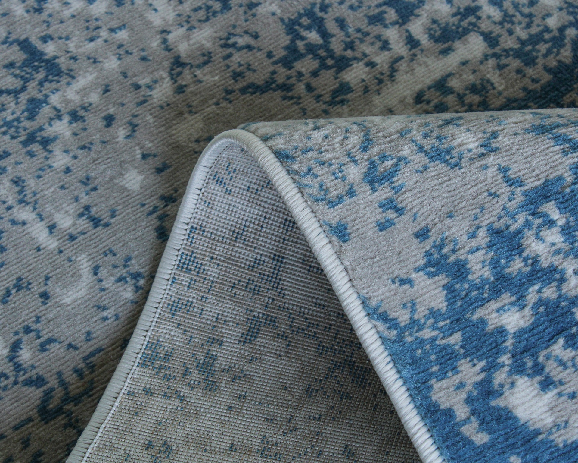 Tapete azul e cinza com padrão abstrato e bordas costuradas