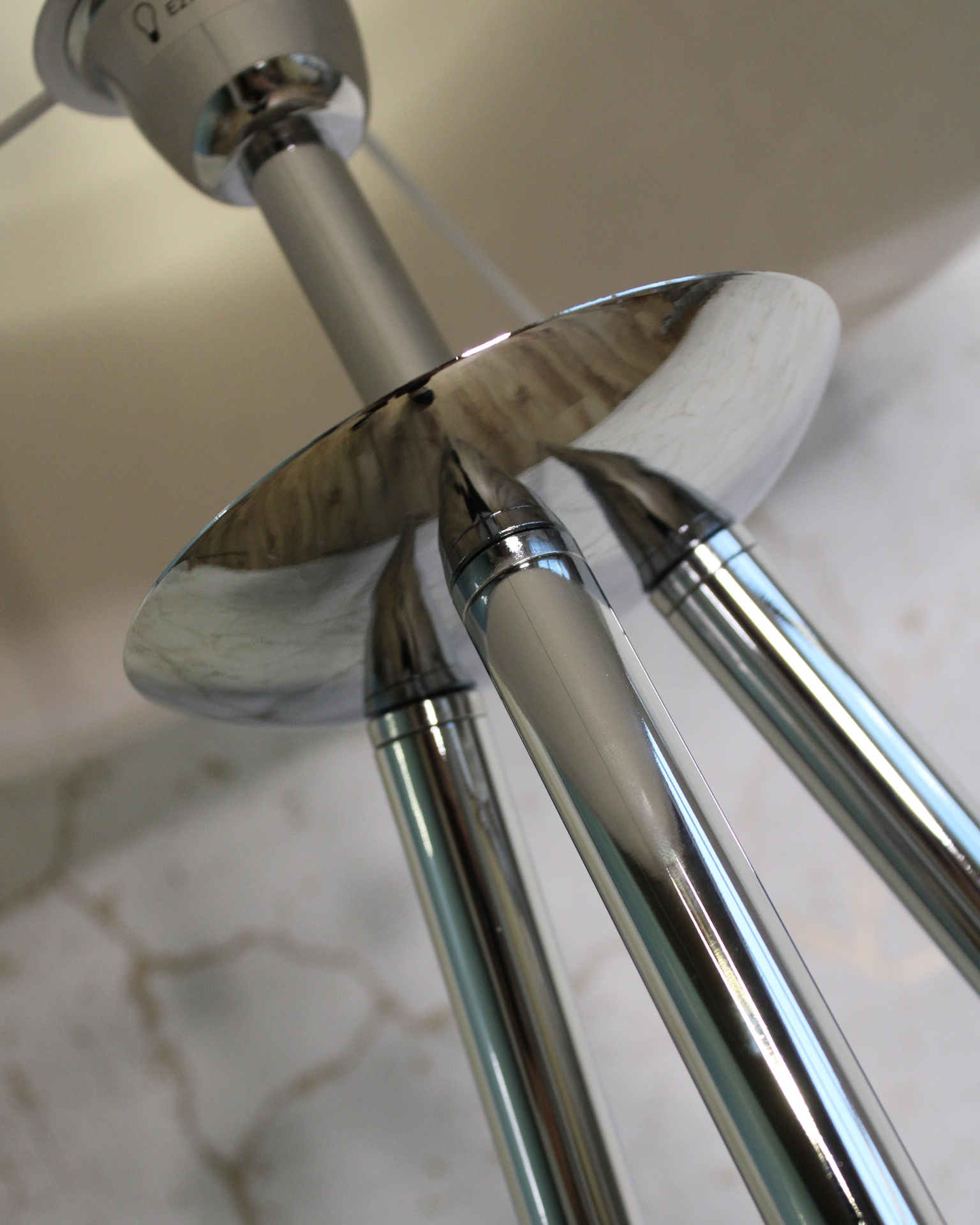 Candeeiro de tecto metálico cromado com três hastes cilíndricas e suporte circular