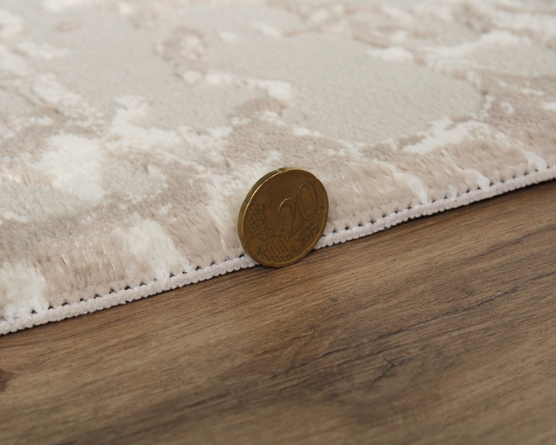 Moeda de 20 cêntimos ao lado de tapete bege com padrão e textura felpuda