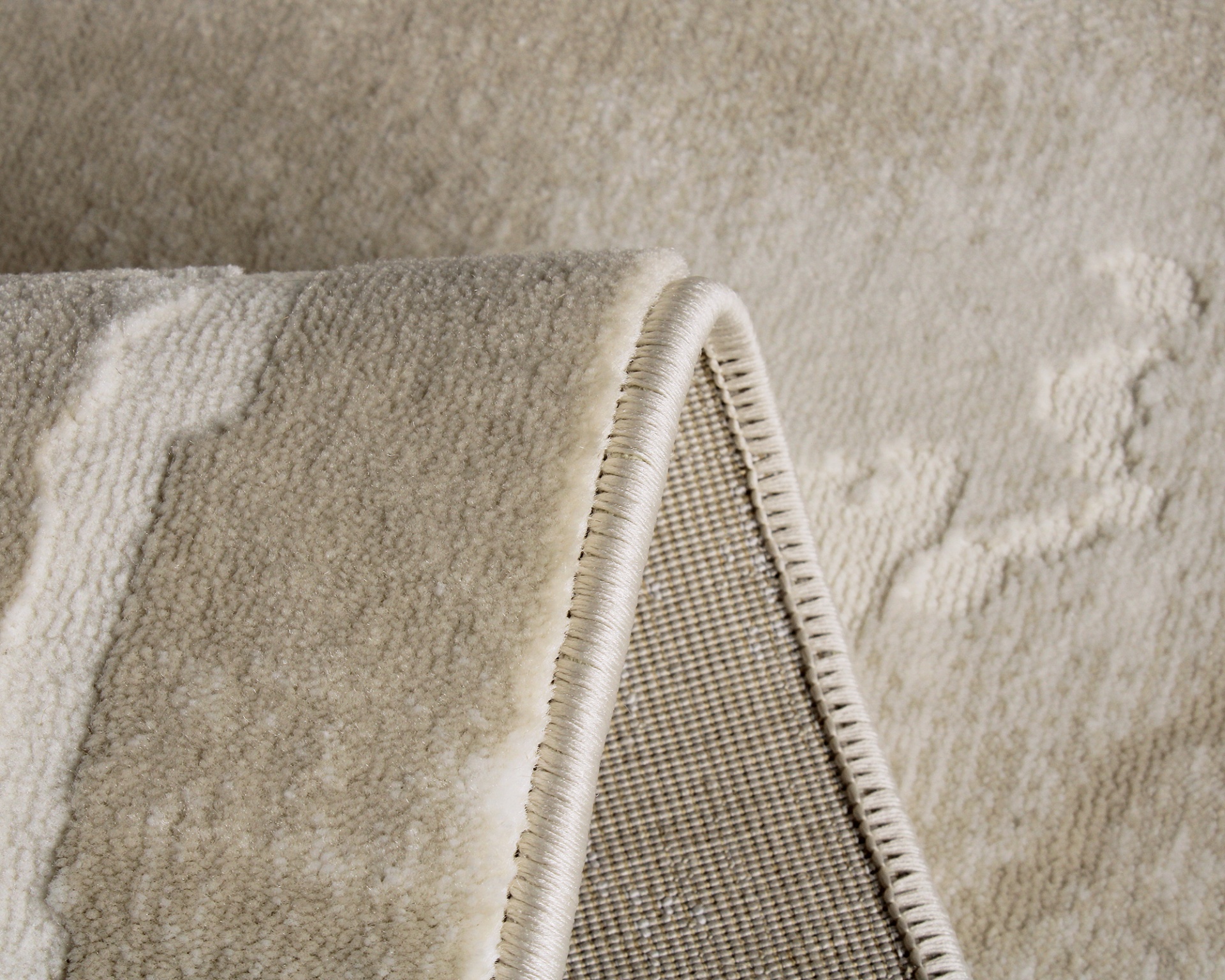 Tapete bege com padrão abstrato e bordas costuradas