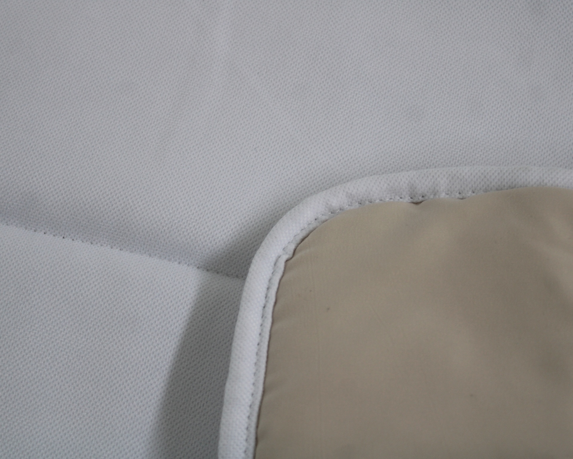 Almofada ou protetor branco com borda arredondada e área bege.