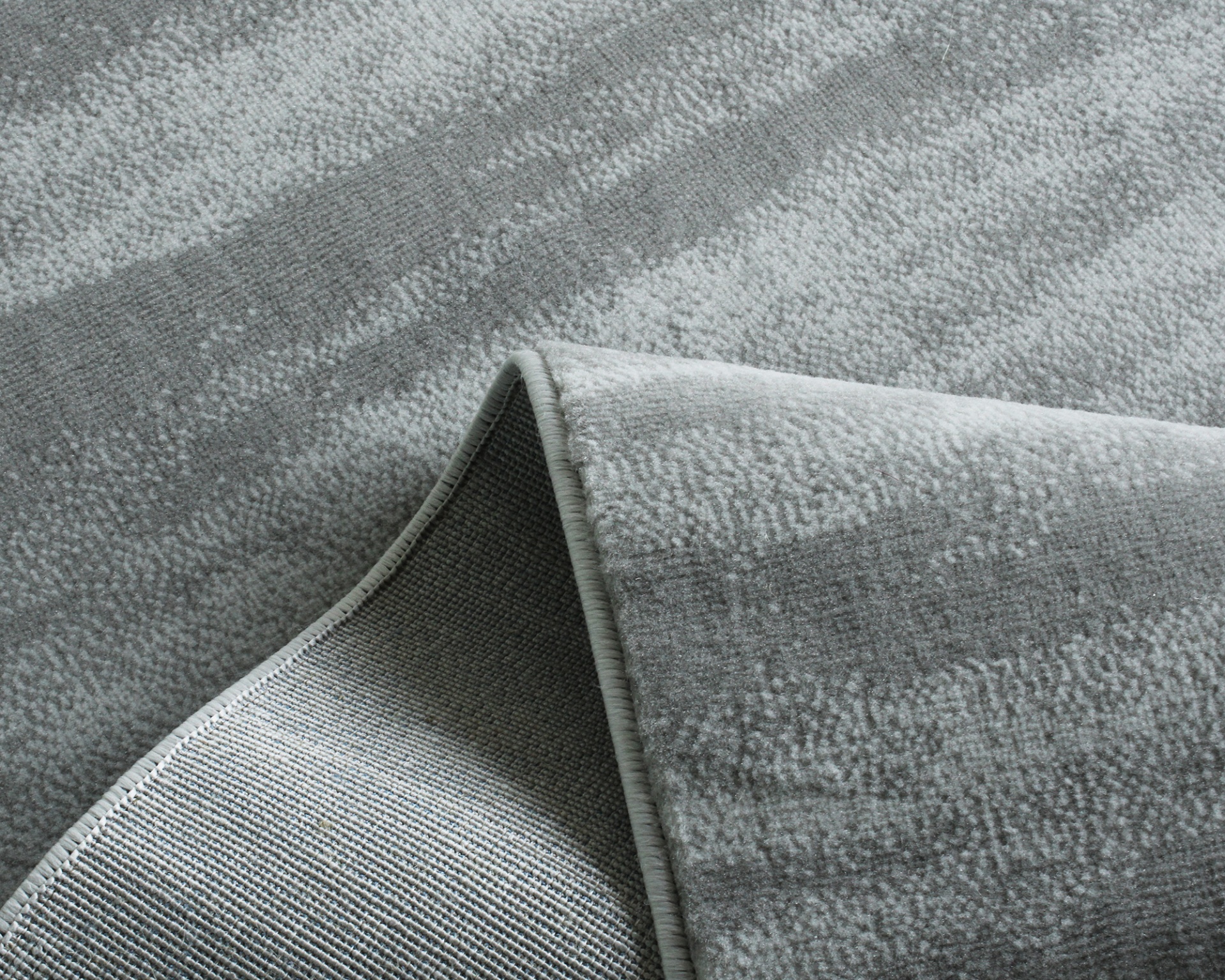 Tapete cinzento com padrão abstrato e bordas costuradas