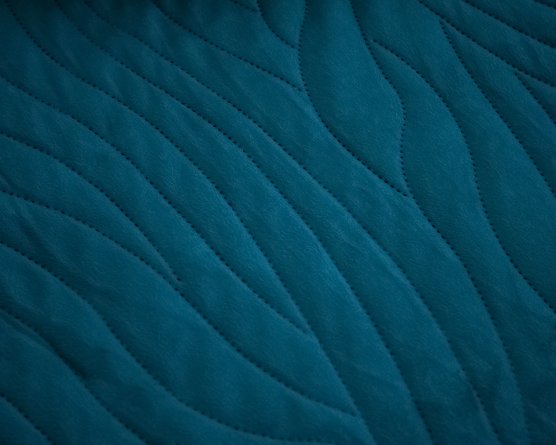 Tecido azul acolchoado com padrão ondulado em relevo