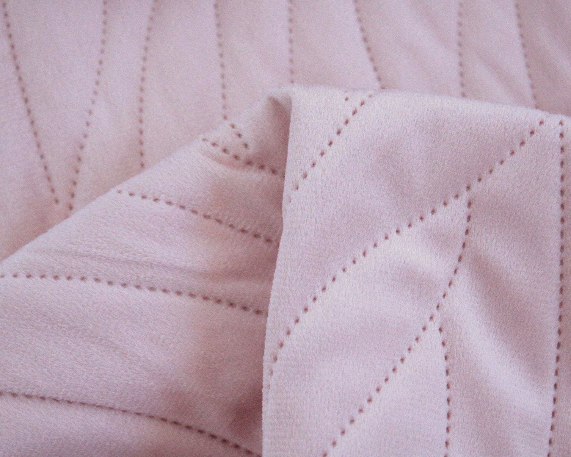 Tecido rosa claro com padrão de linhas perfuradas geométricas