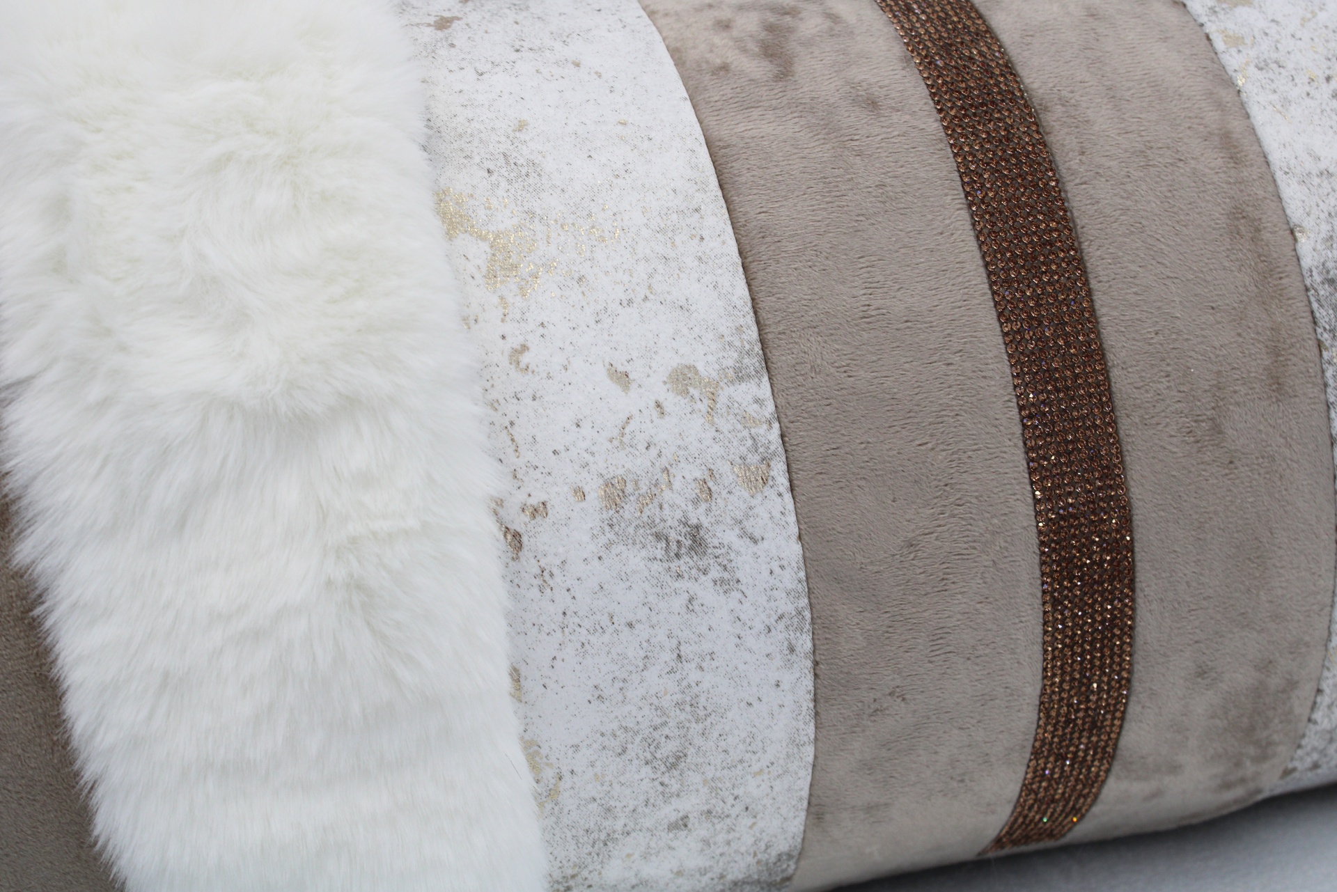 Três almofadas decorativas em tons bege e branco com texturas variadas