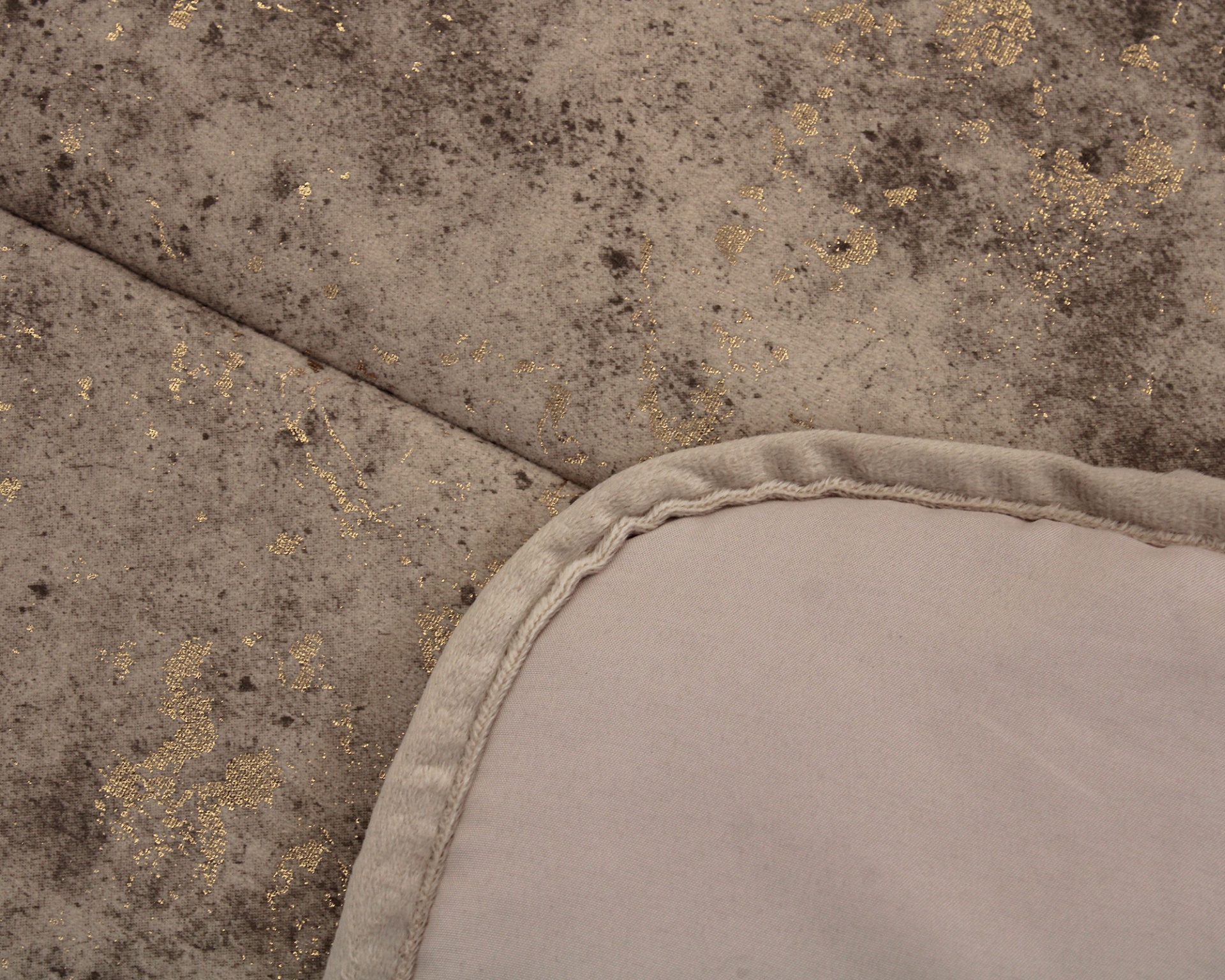 Detalhe de tecido marmoreado cinza e dourado com bordas arredondadas bege