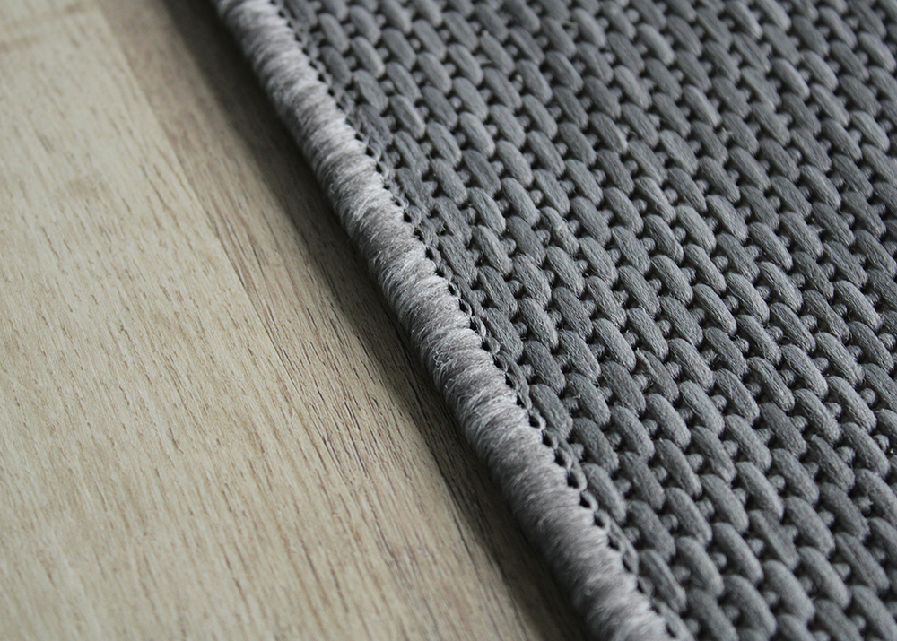 Tapete cinzento tecido sobre chão de madeira clara