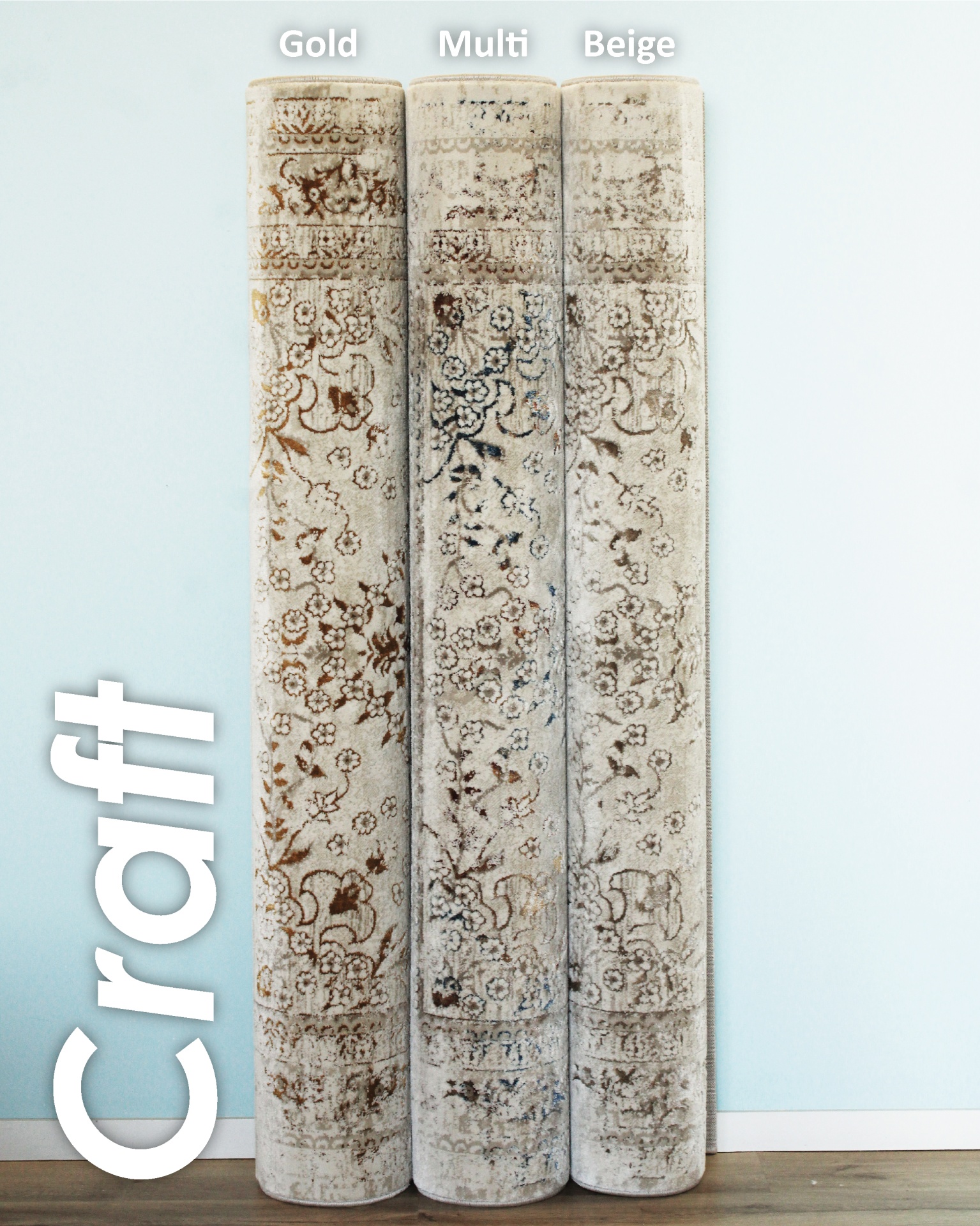 Três tapetes enrolados com padrão floral em tons bege, castanho e azul encostados na parede azul clara