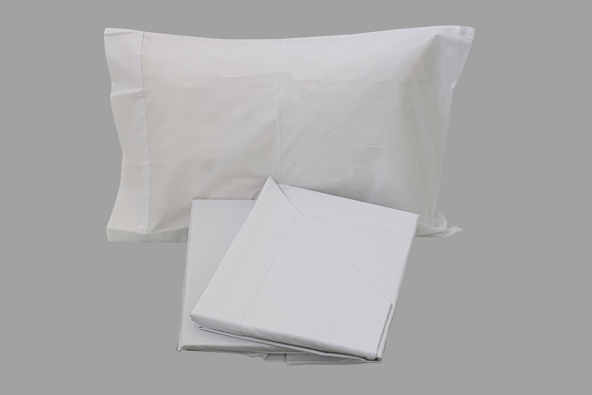 Conjunto de roupa de cama branca composto por fronha e lençóis dobrados