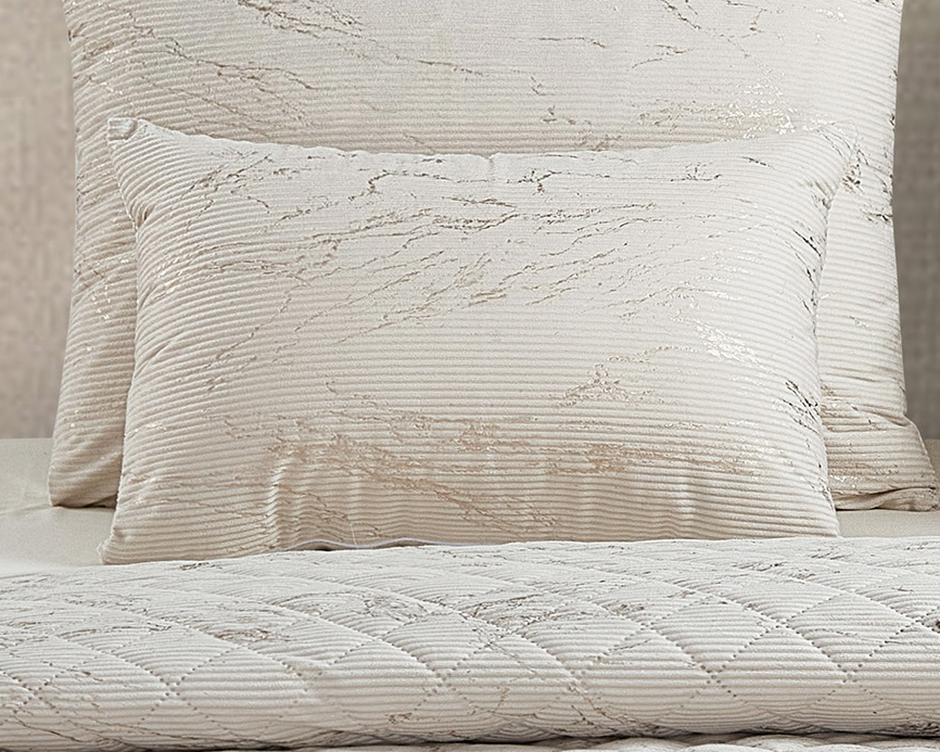 Conjunto de almofadas e colcha creme com padrão texturizado em cama