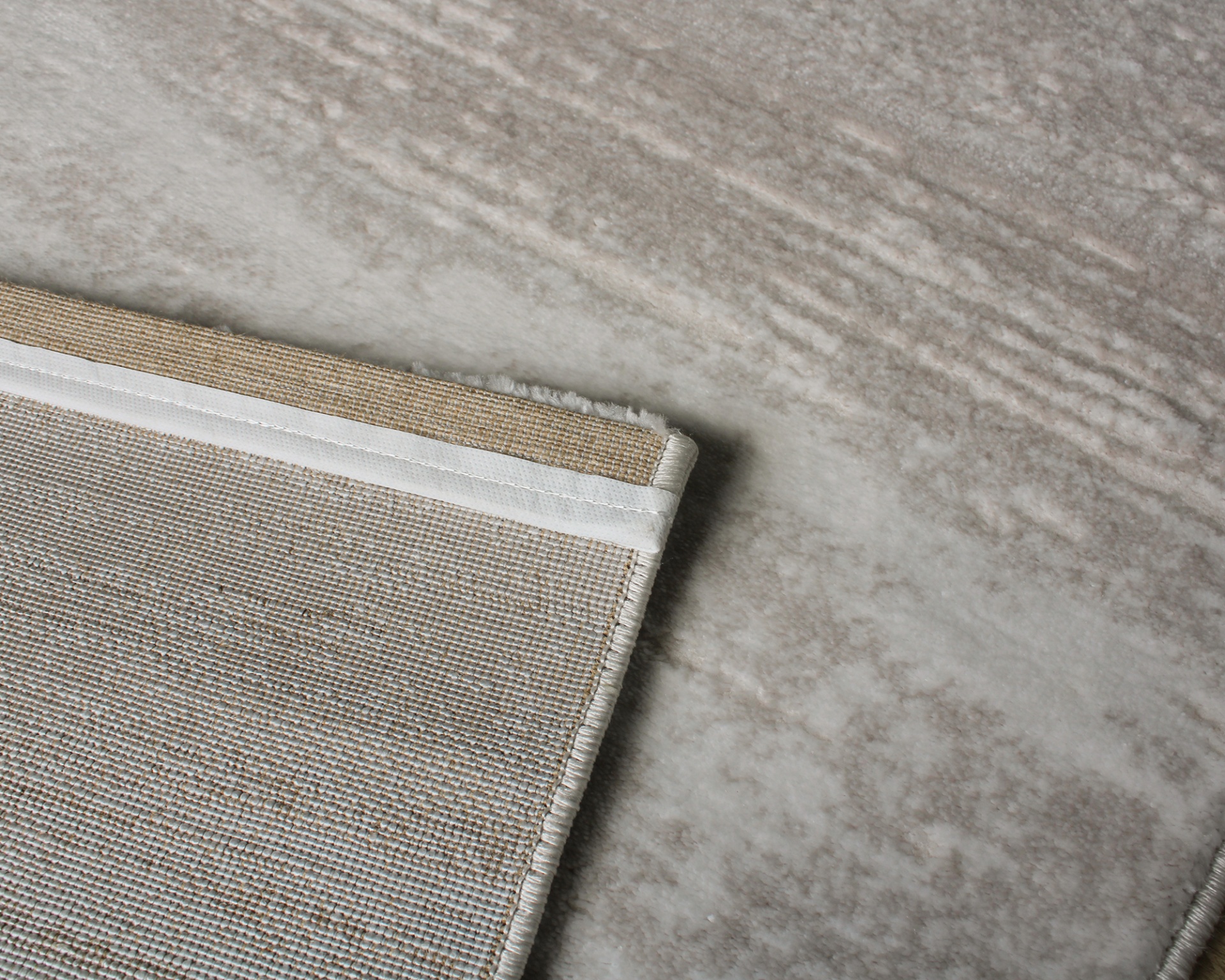 Tapete bege com borda branca sobre piso cinza claro