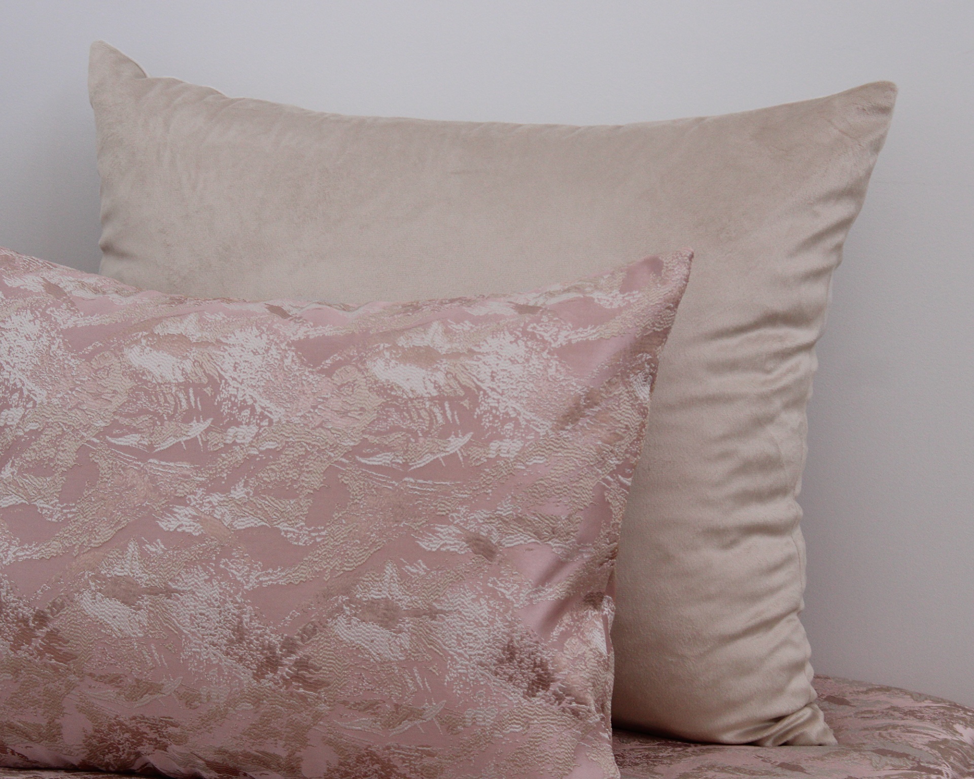 Duas almofadas, uma bege lisa e outra rosa com padrão abstrato
