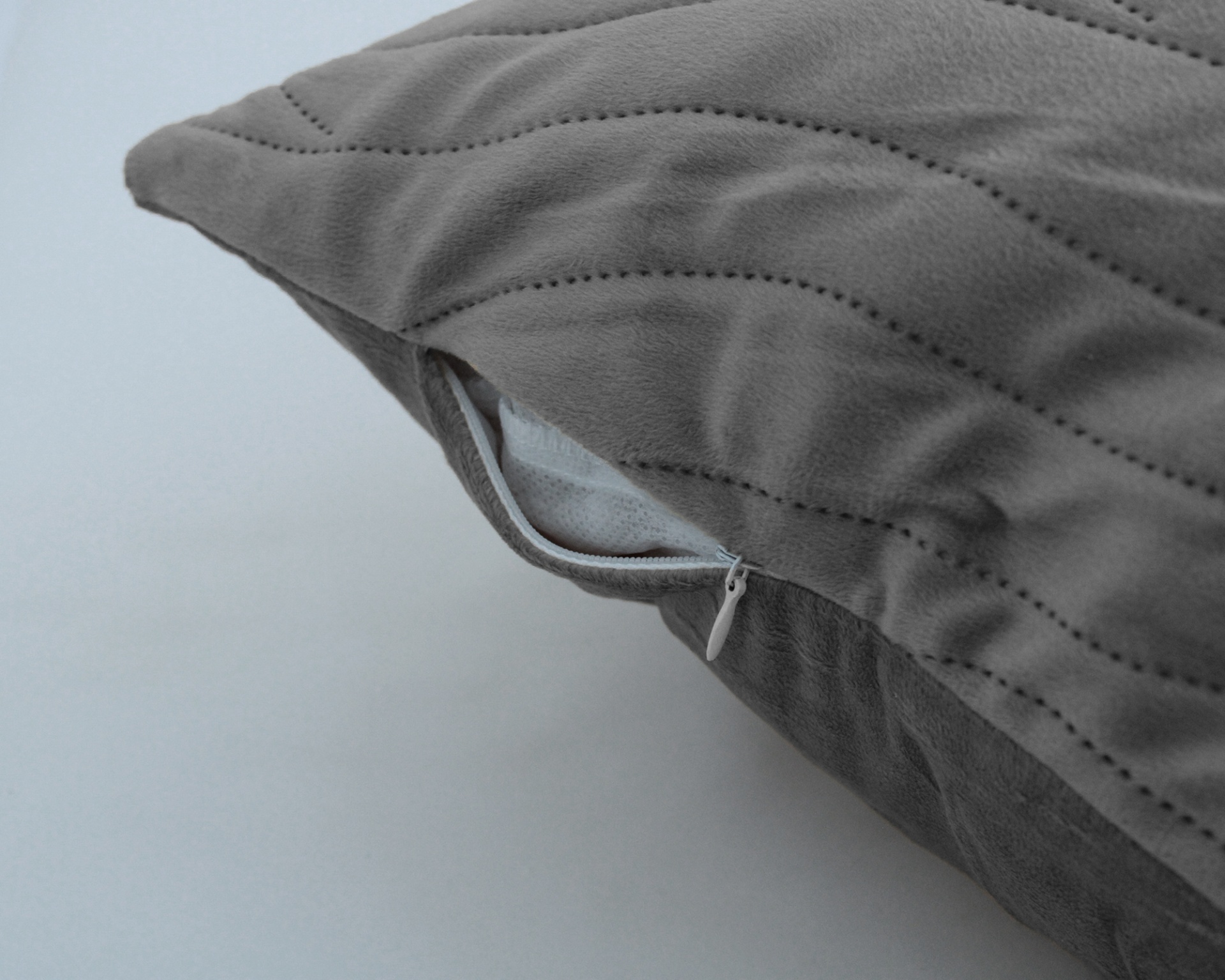 Almofada cinzenta com padrão linhas costeadas e fecho de correr branco