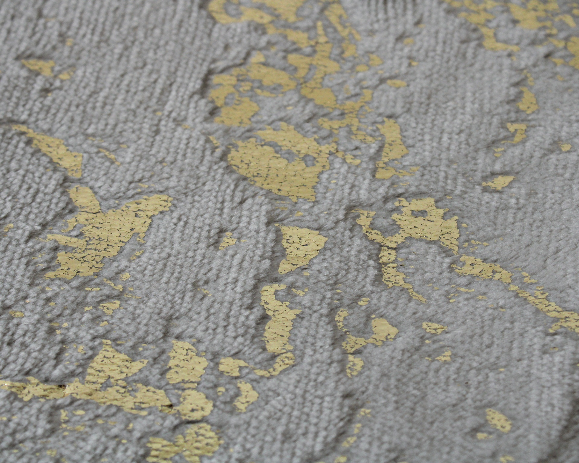 Tecido cinzento com padrão dourado irregular e textura em relevo