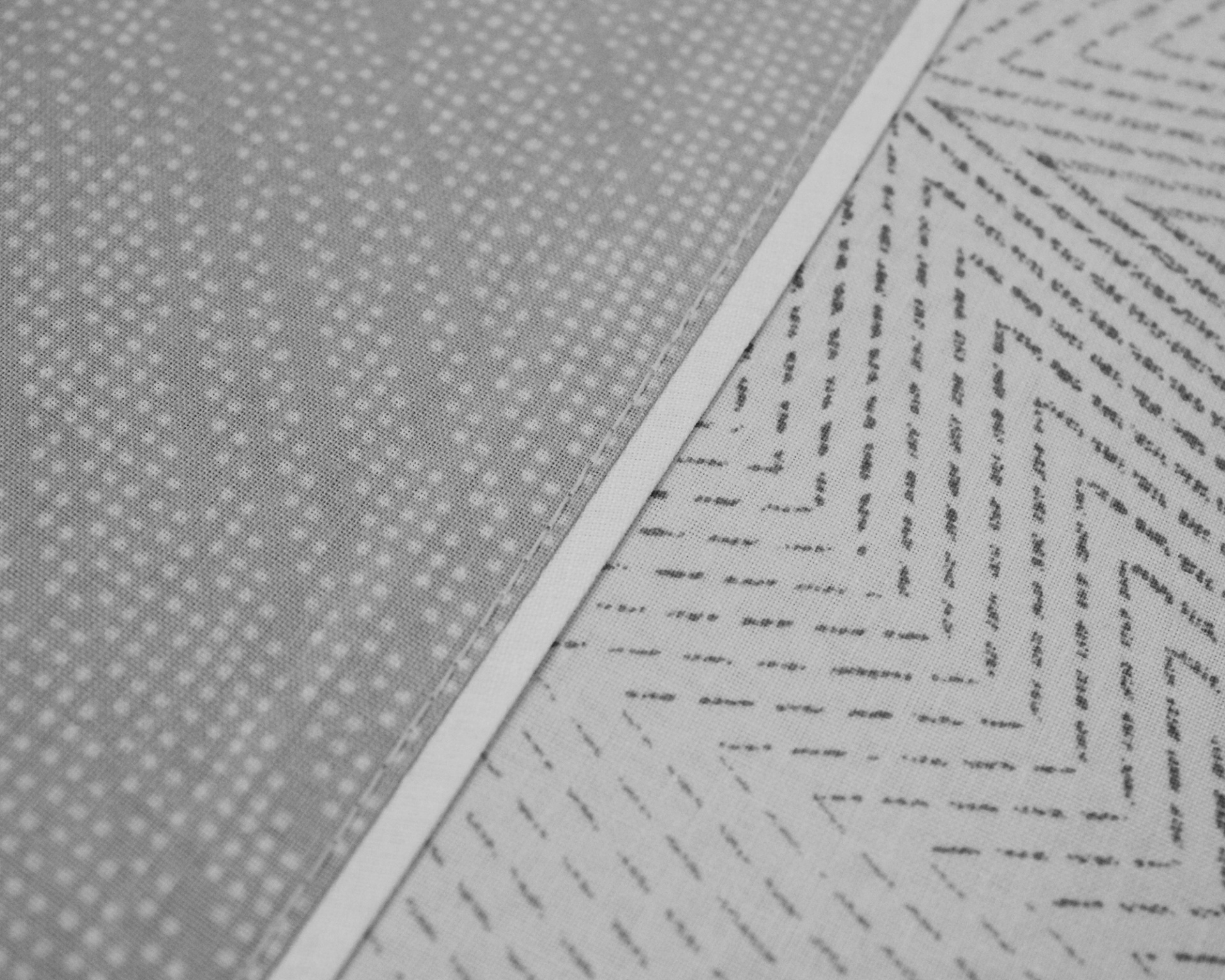 Dois tapetes com padrões geométricos, um cinza com pontos brancos e outro branco com linhas pretas em zigue-zague