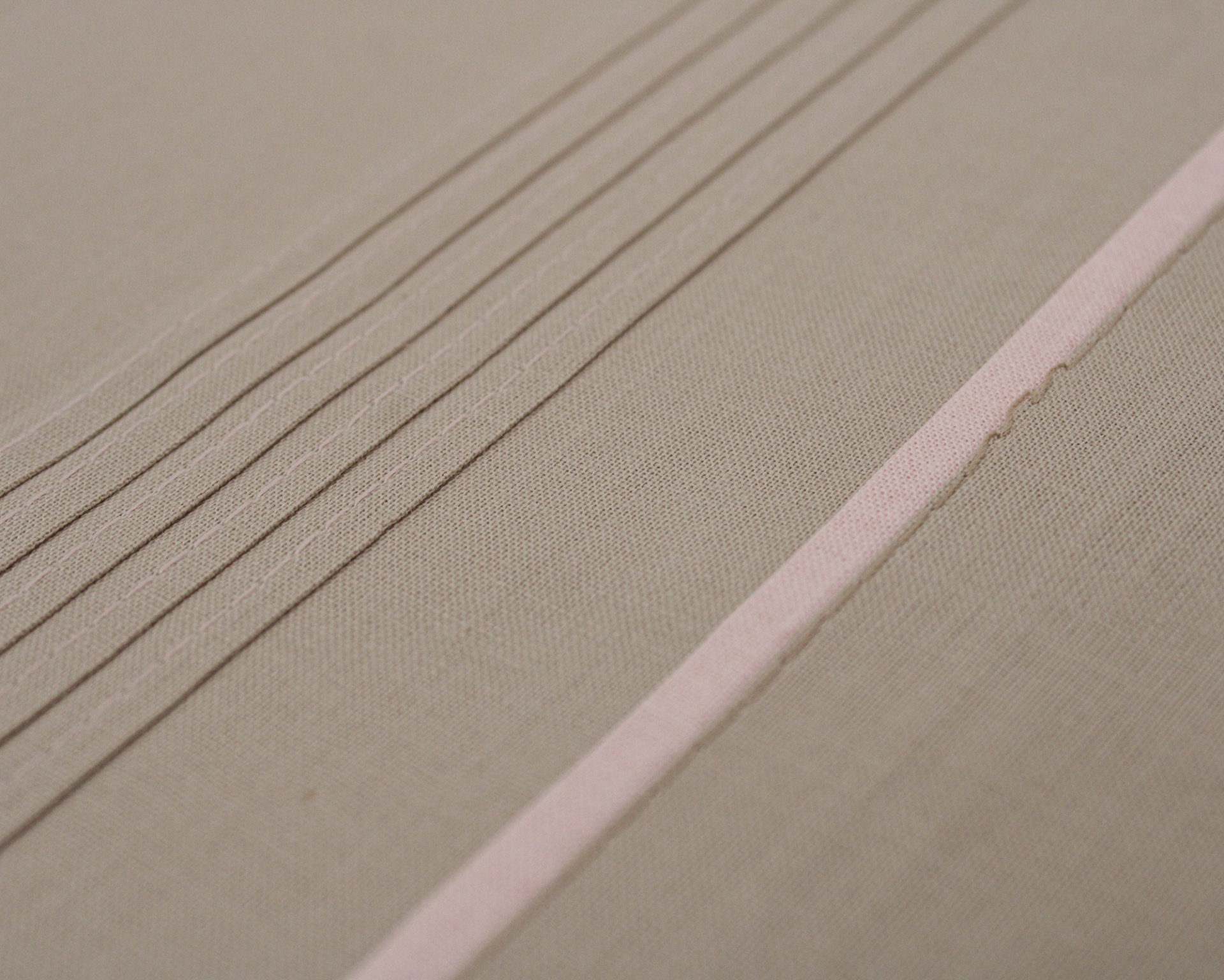 Tecido bege com linhas finas paralelas e faixa rosa clara