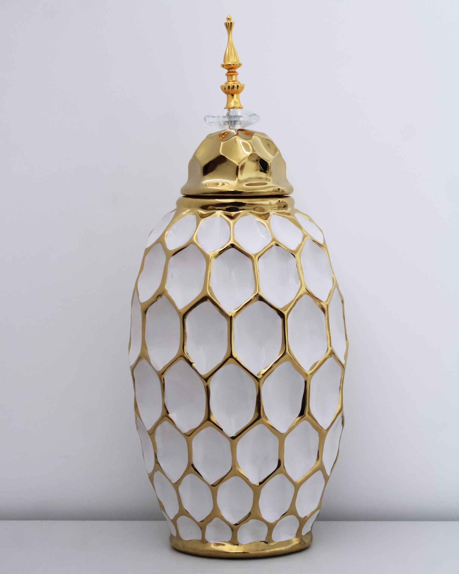Jarro decorativo branco com padrões dourados e tampa dourada