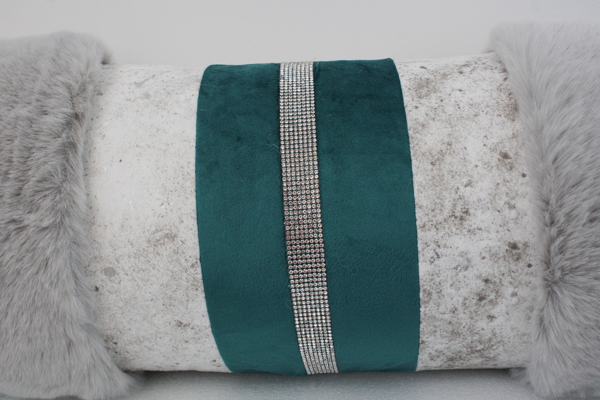 Travesseiro branco com faixa verde e strass prateados, bordas de pelúcia cinza