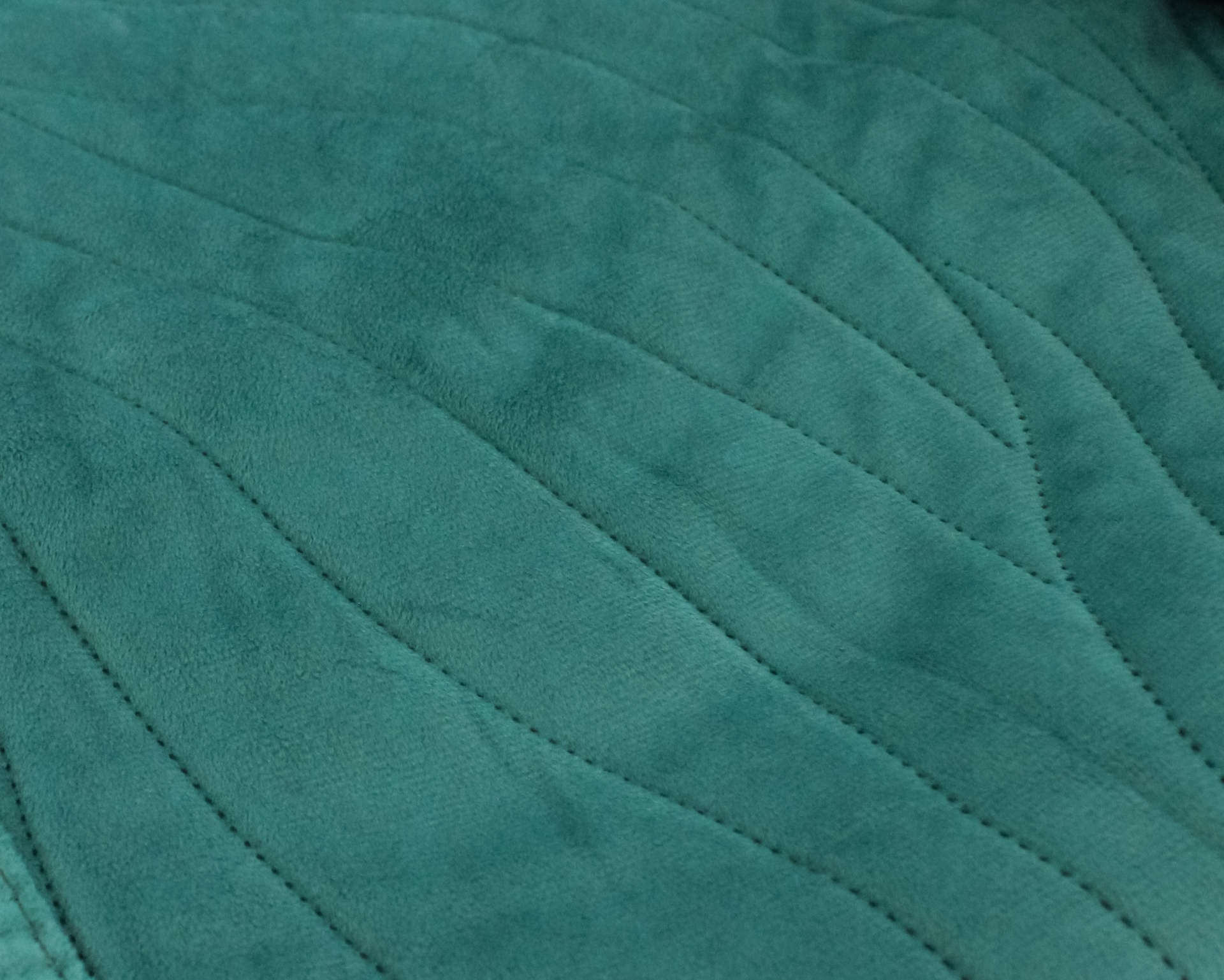 Tecido verde turquesa com padrão de linhas onduladas costuradas