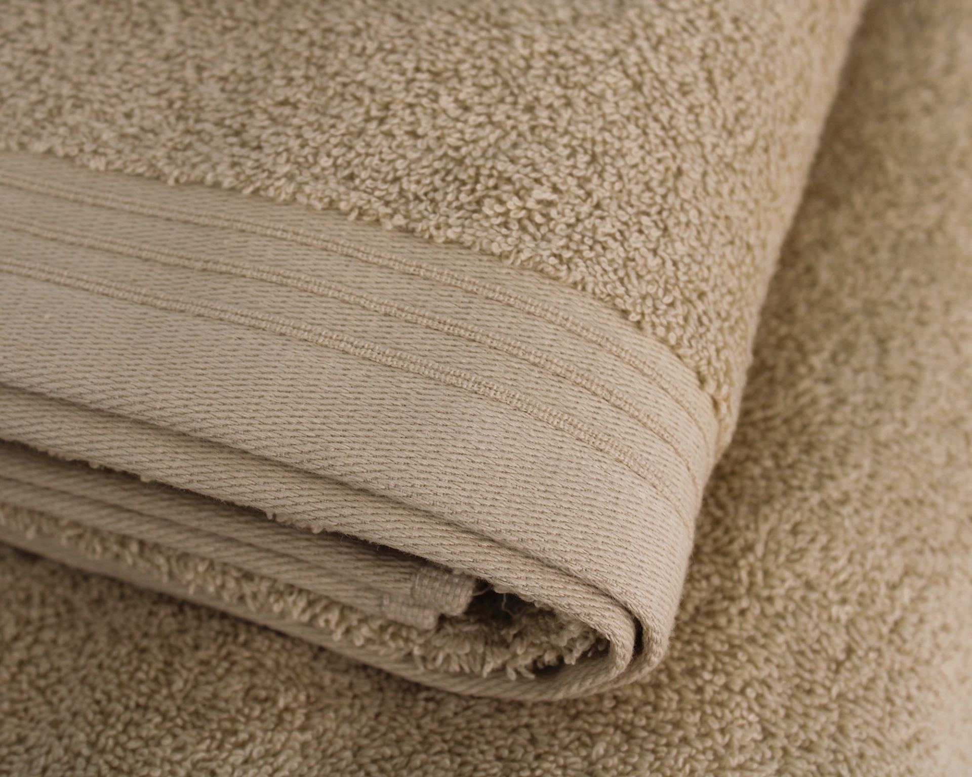 Toalha bege dobrada com textura felpuda e borda lisa