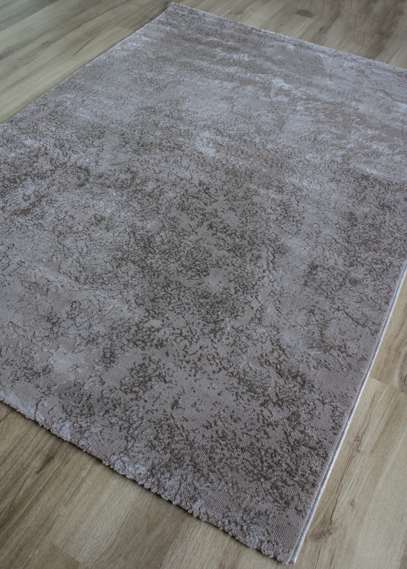 Tapete cinzento com padrão abstrato sobre chão de madeira clara