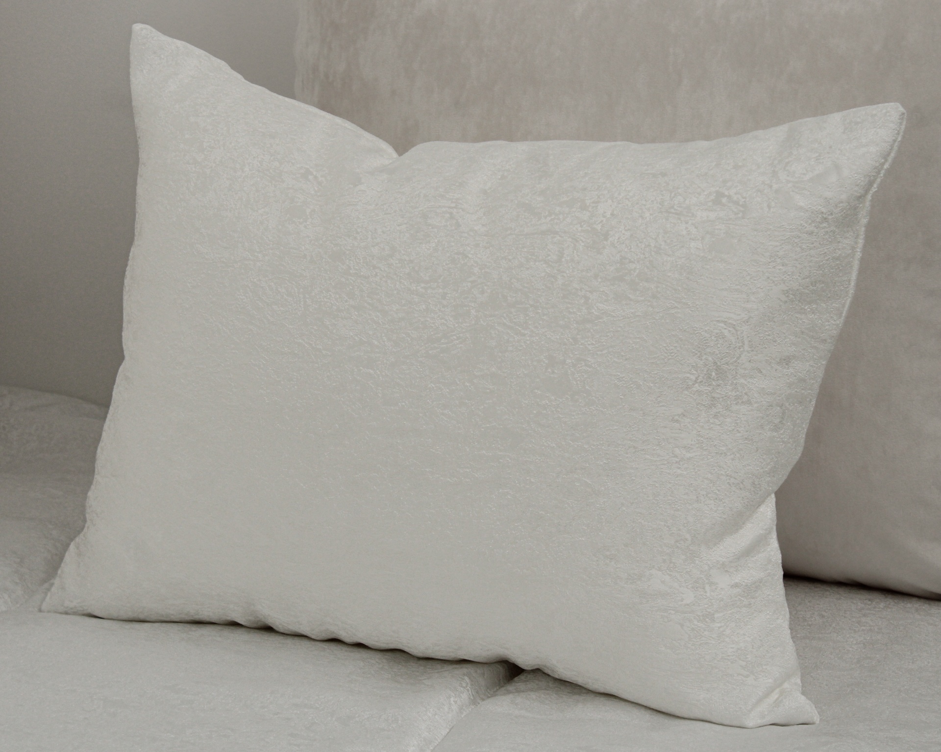 Travesseiro branco retangular com textura sobre superfície cinza claro