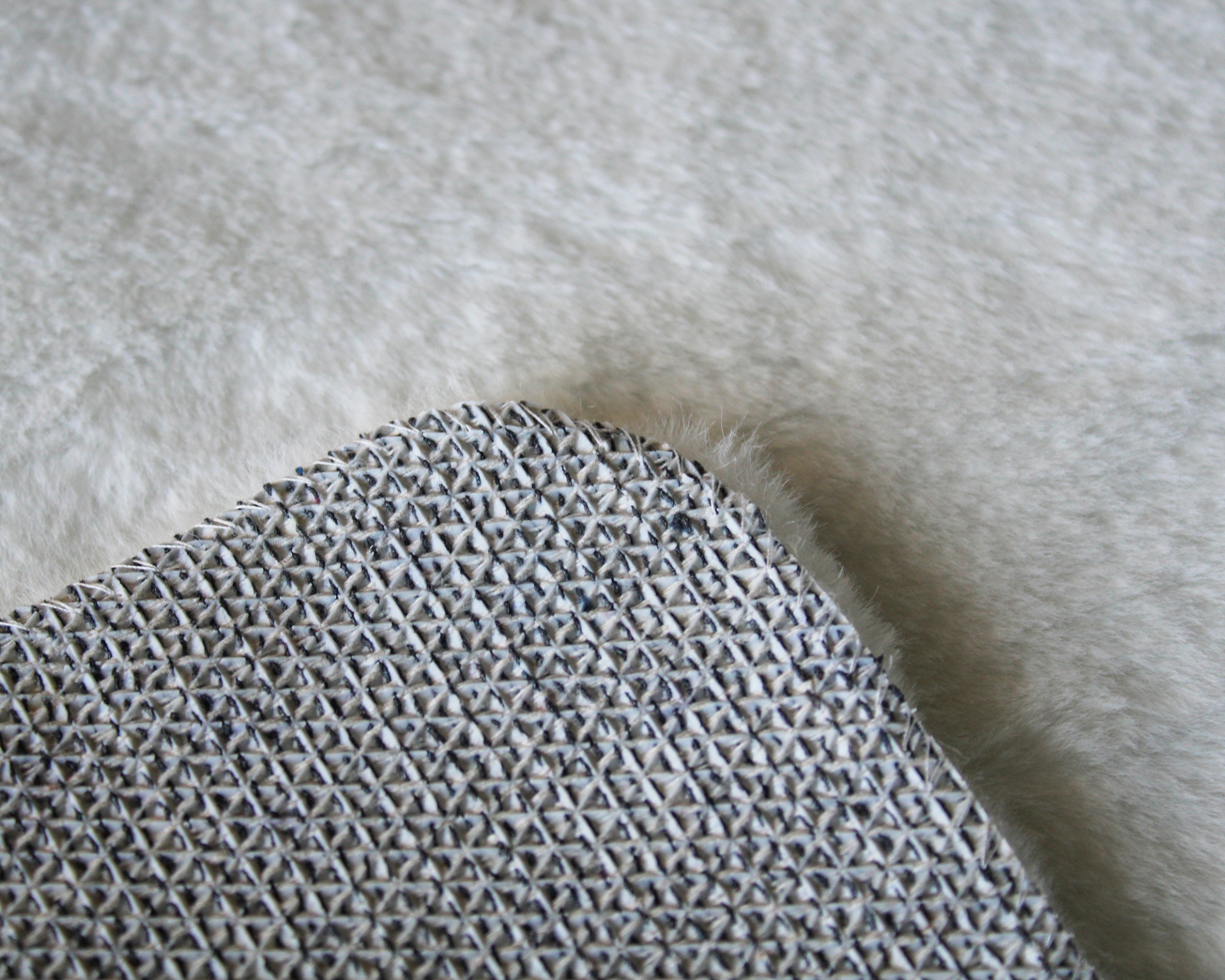 Tapete cinzento texturizado sobre superfície peluda clara