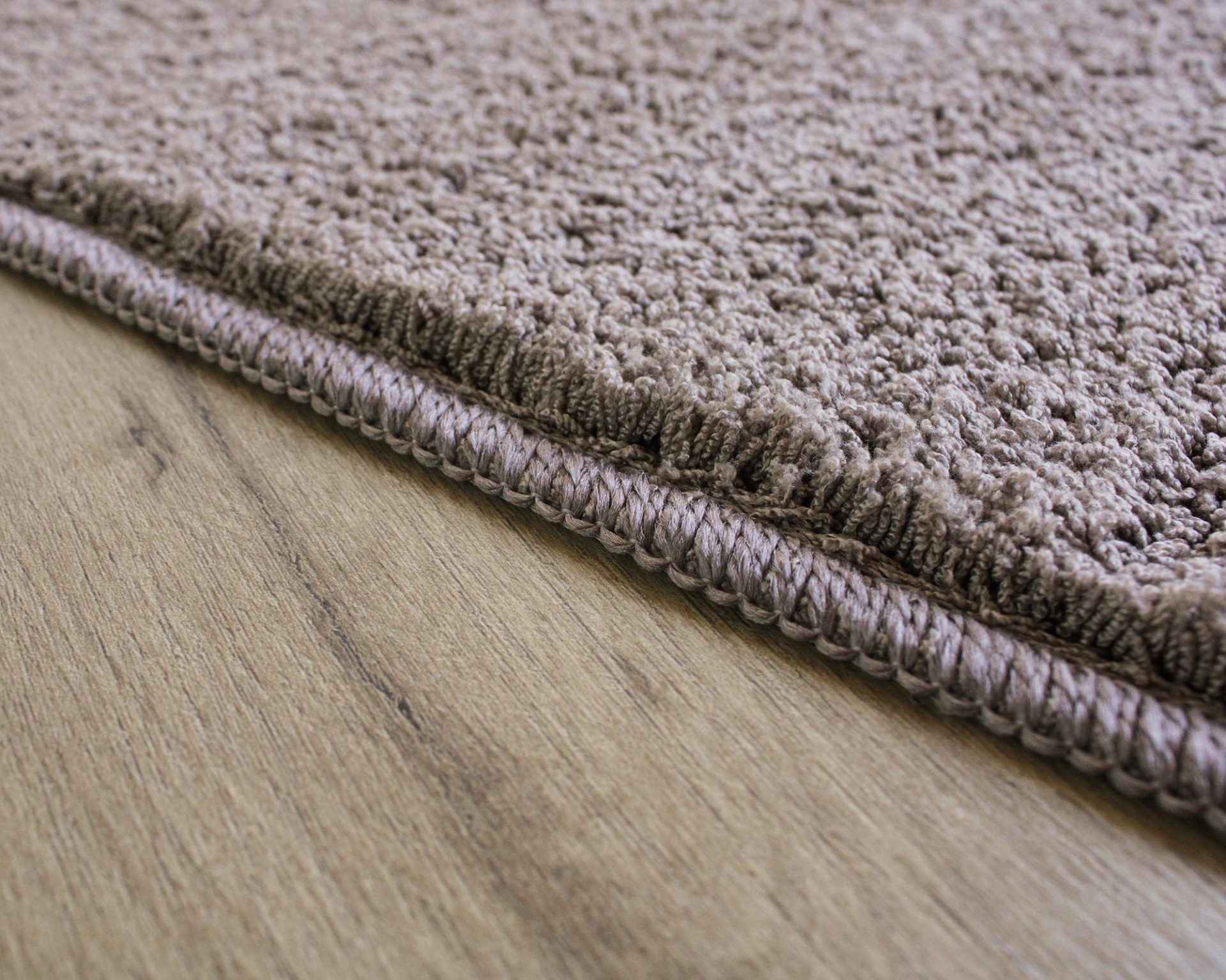 Tapete castanho claro com textura felpuda sobre chão de madeira clara