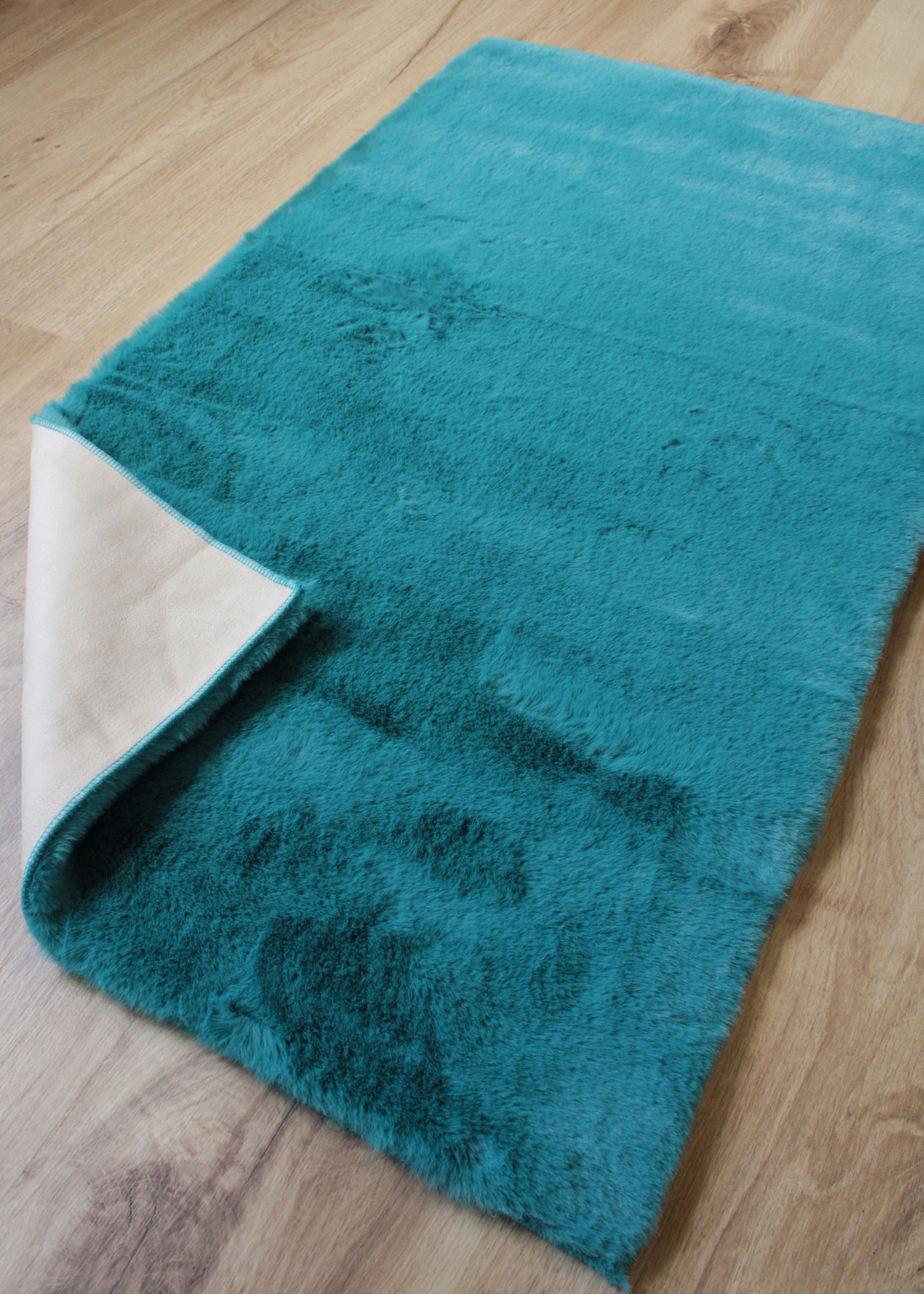 Tapete azul-turquesa com base branca sobre chão de madeira clara