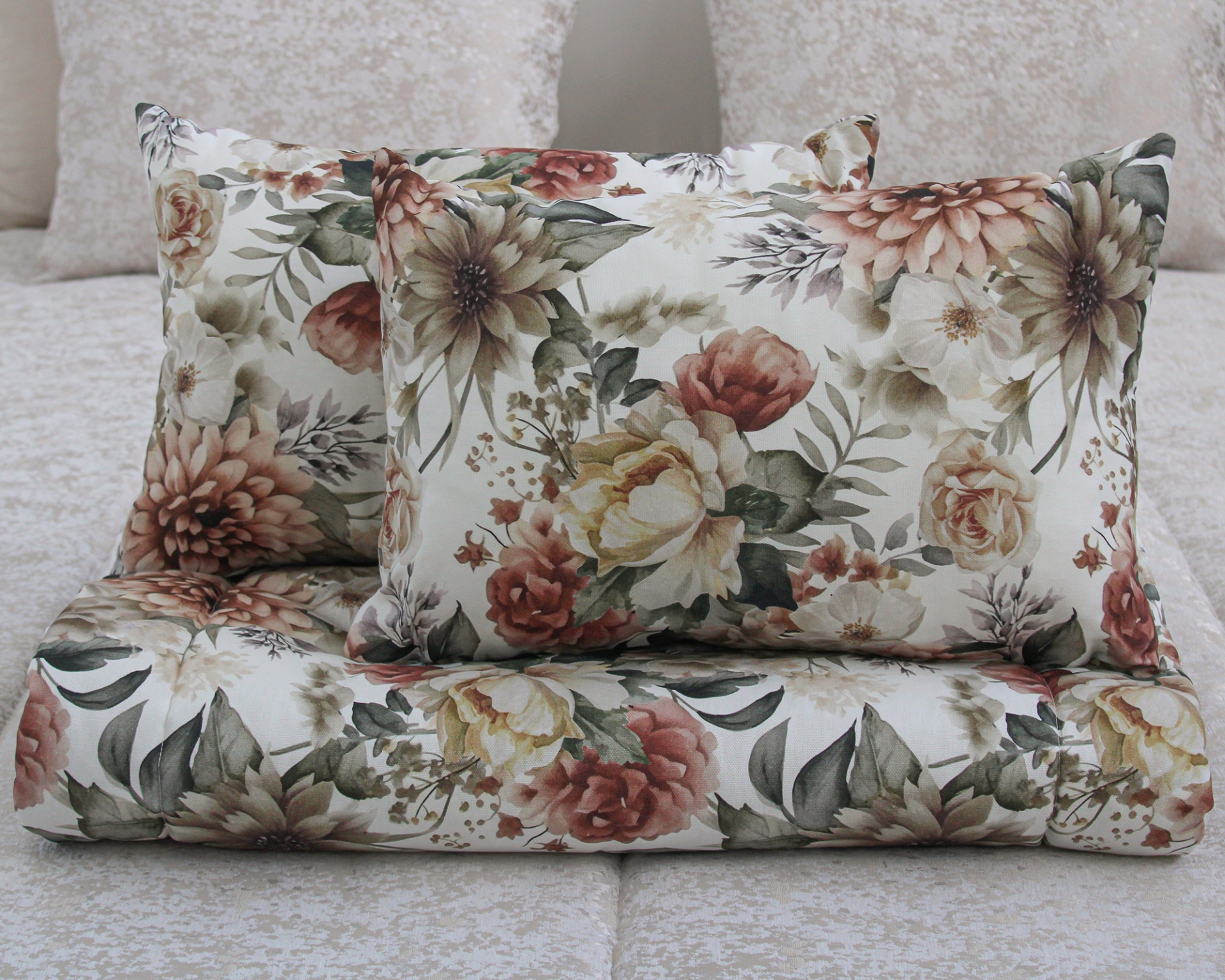 Conjunto de cama com capa e almofadas florais sobre cama bege