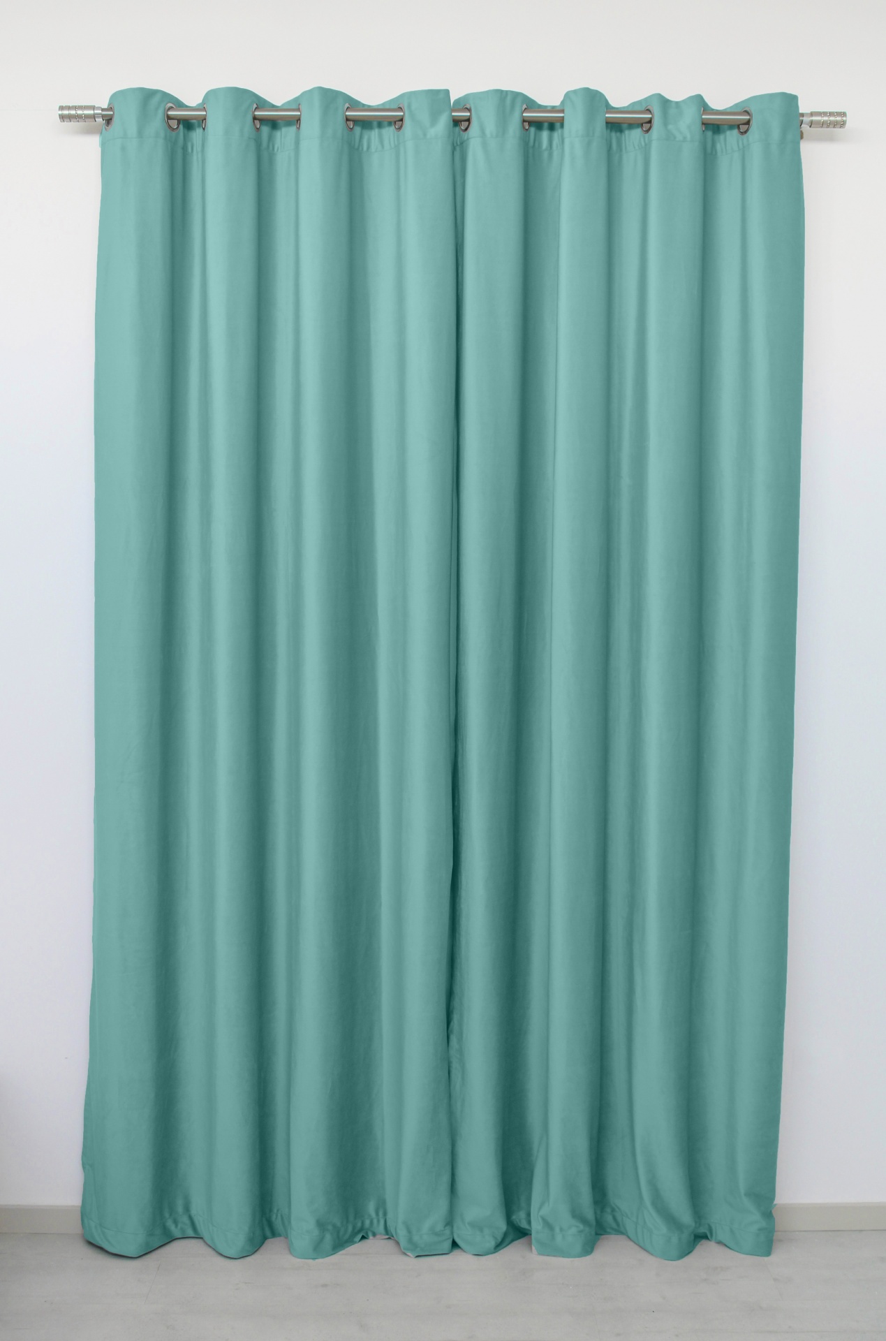 Cortina azul turquesa em tecido com ilhós prateados suspensa numa barra metálica contra parede branca