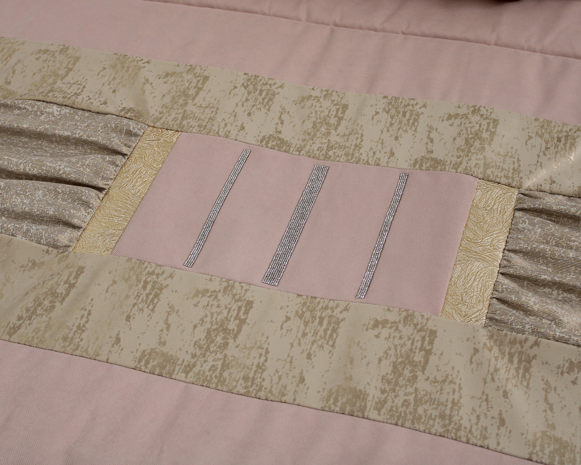 Colcha rosa claro com detalhes em bege e dourado com textura e listas verticais metálicas