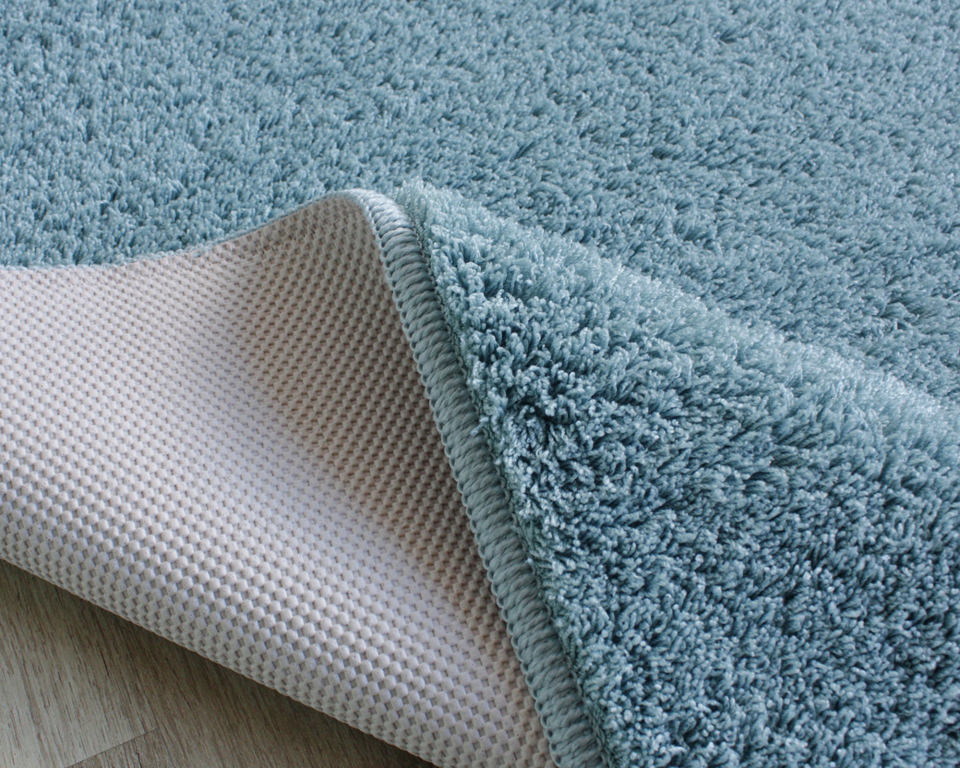 Tapete azul claro com base antiderrapante sobre chão de madeira