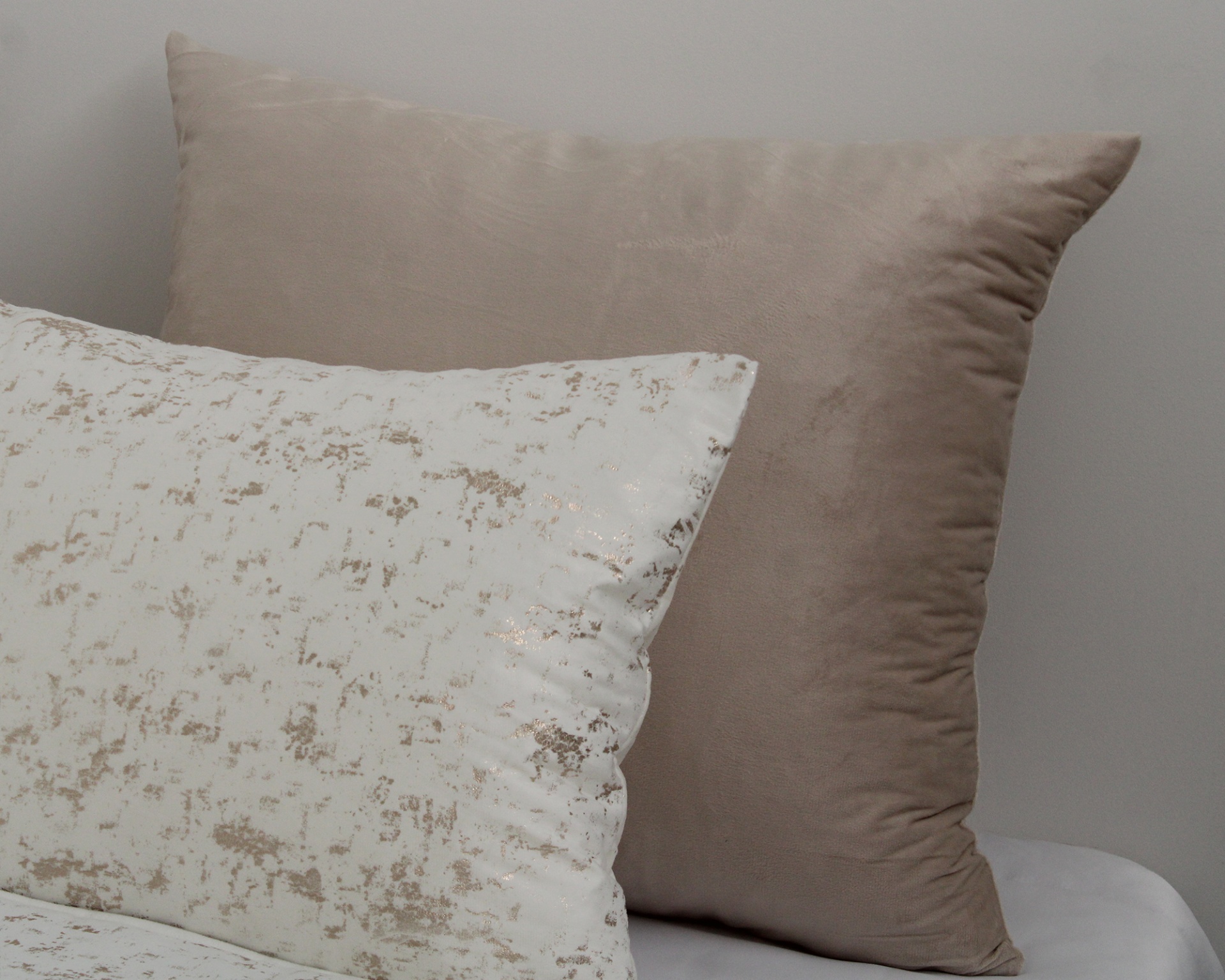 Três almofadas de cama brancas e bege com padrão dourado e liso