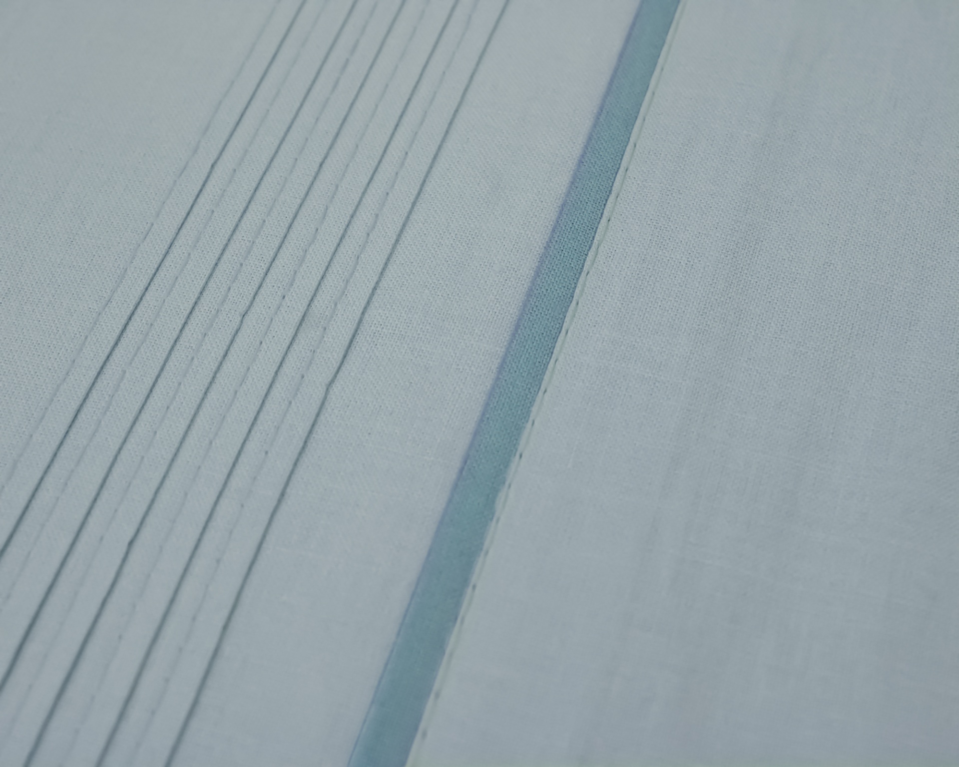 Tecido azul claro com pregas paralelas e linha azul escura central