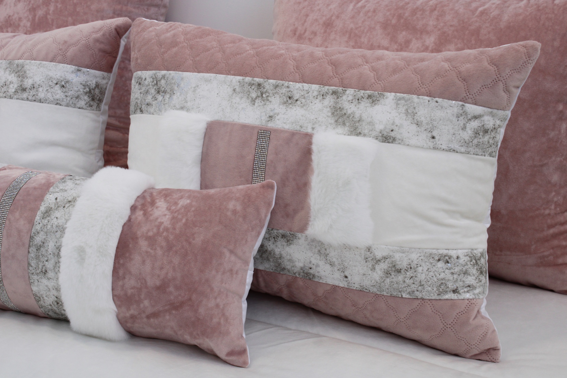 Almofadas decorativas em rosa, branco e cinza com texturas variadas