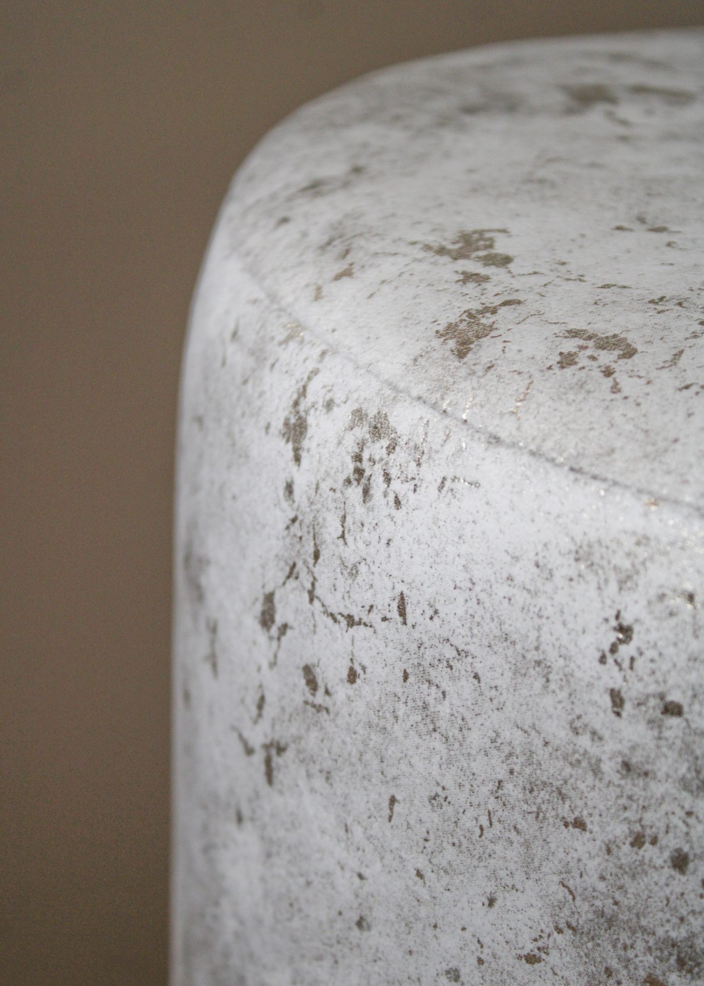 Cilindro branco com manchas cinzentas em fundo bege desfocado