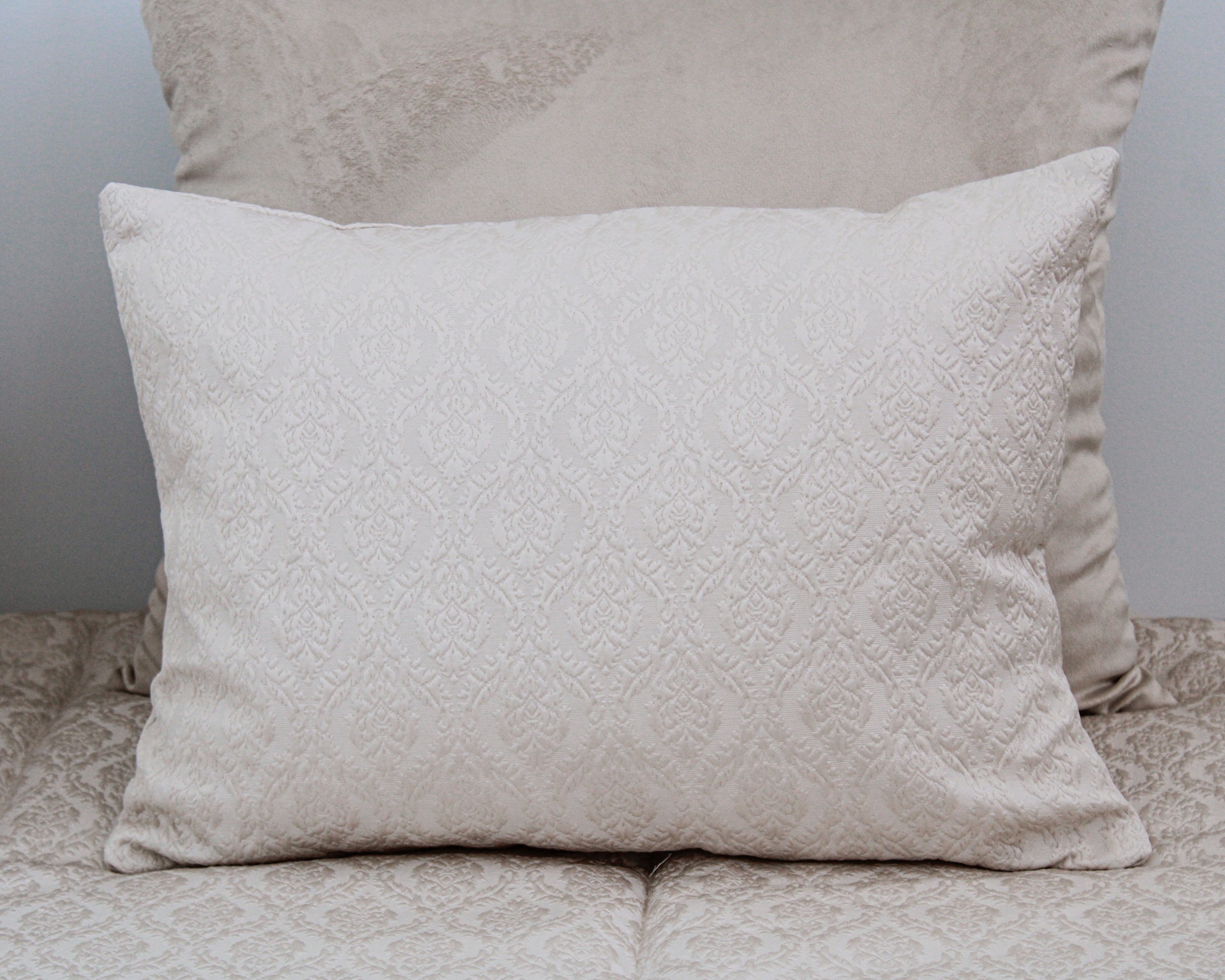 Almofada creme com padrão floral texturizado em relevo