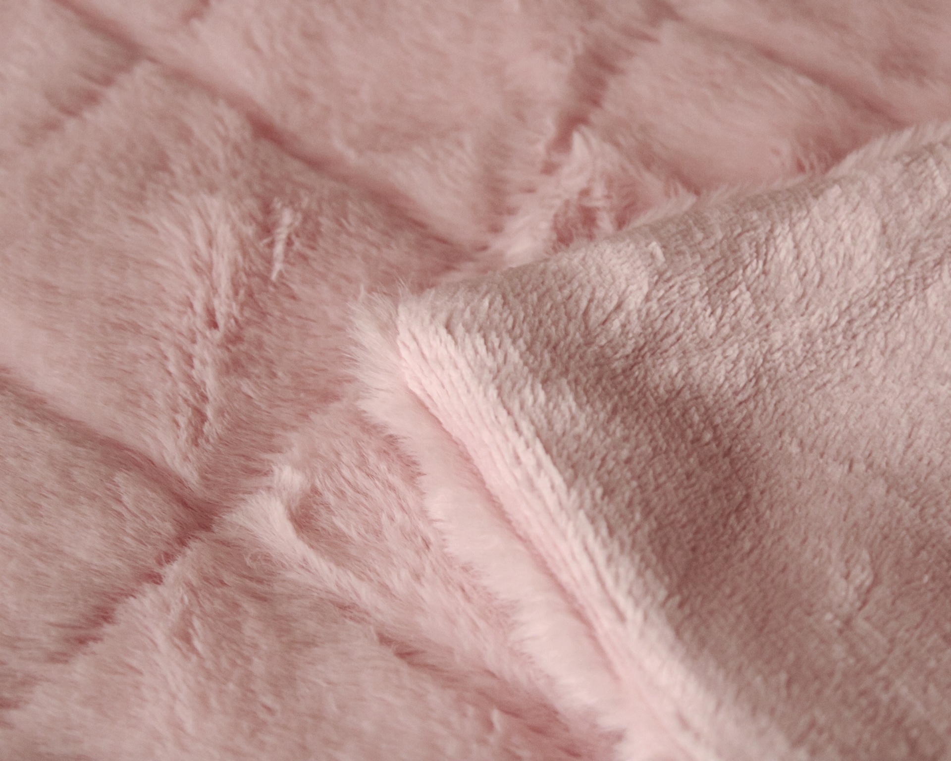 tecido de pelúcia rosa com padrão acolchoado e parte dobrada mostrando o verso