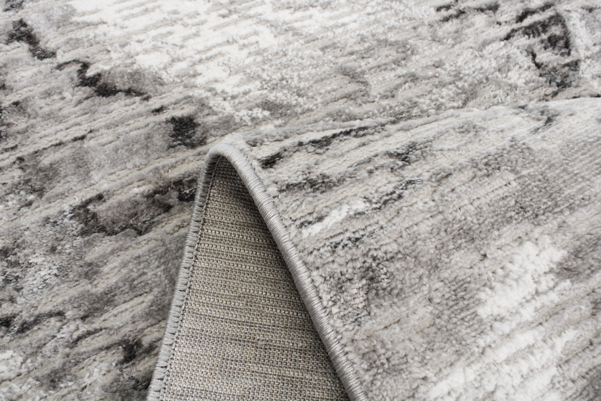 Tapete cinza abstrato com borda costurada e verso trançado