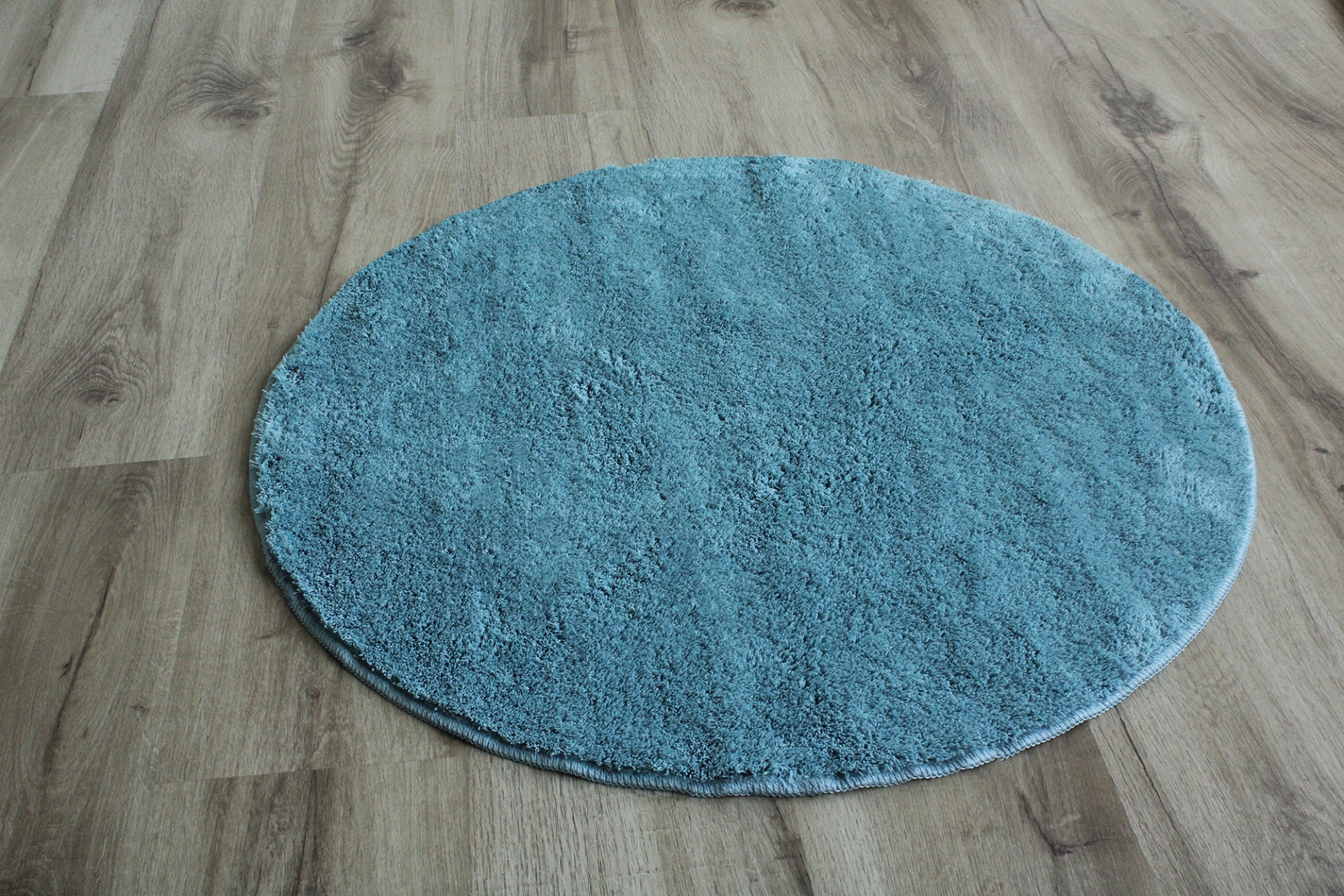 Tapete redondo azul claro sobre chão de madeira