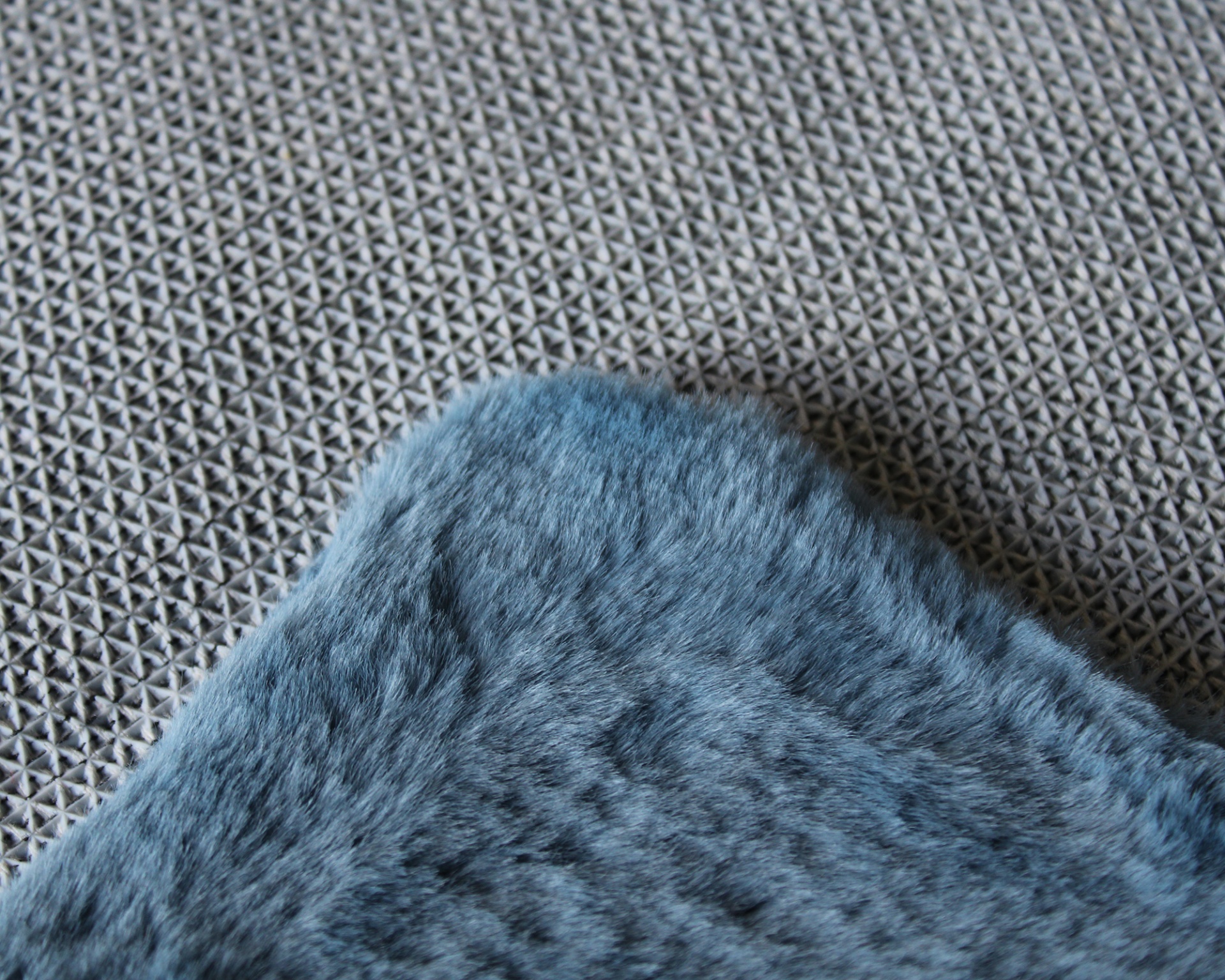 Tapete cinzento com padrão triangular e canto de tapete azul felpudo