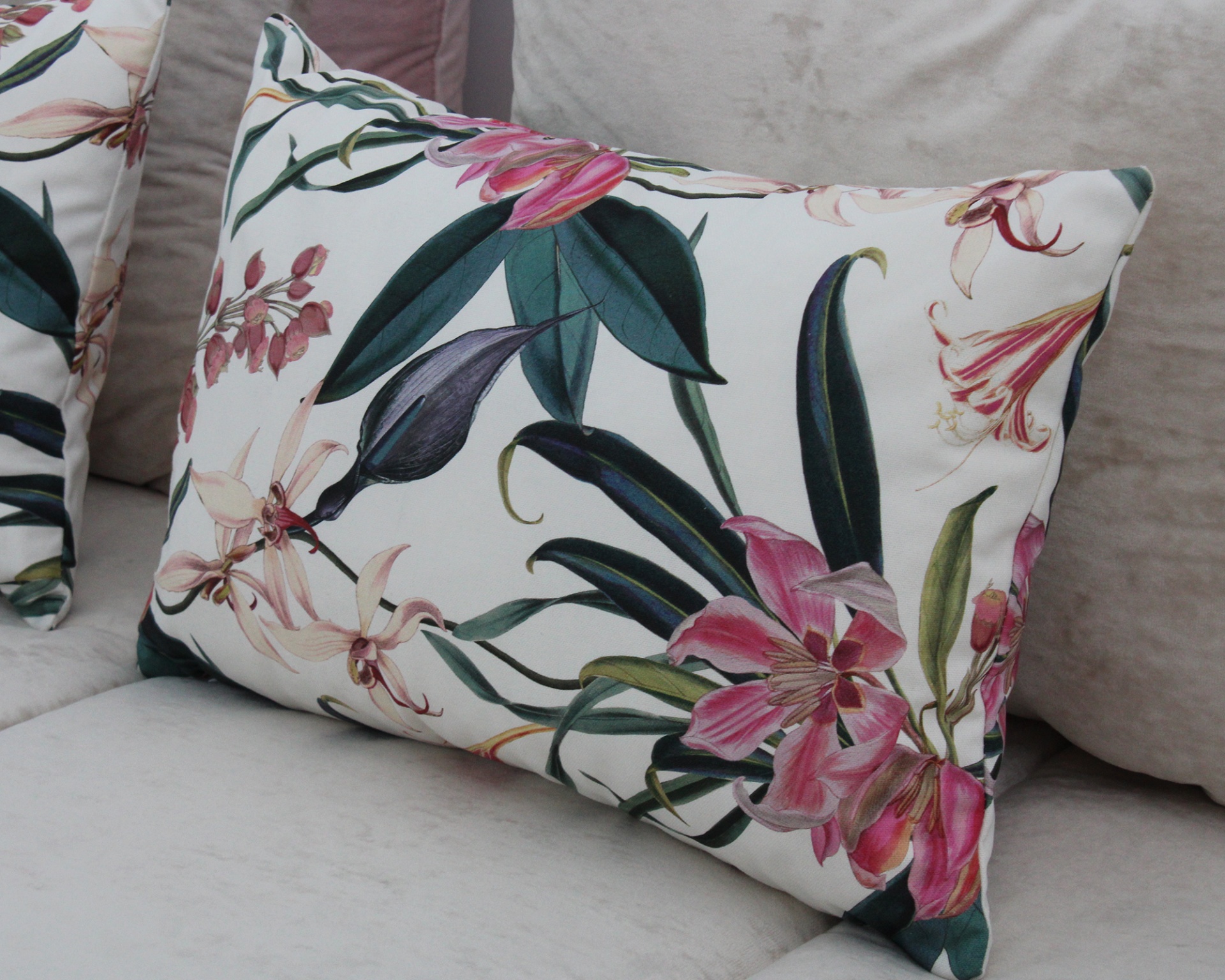 Travesseiro com estampa floral rosa e verde num sofá cinza claro