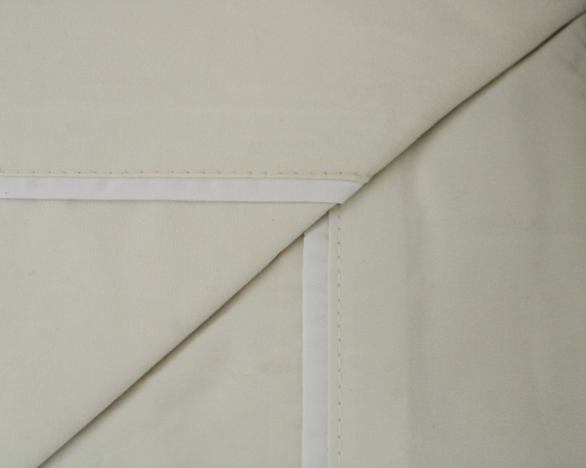 tecido bege claro com costuras e bordas brancas