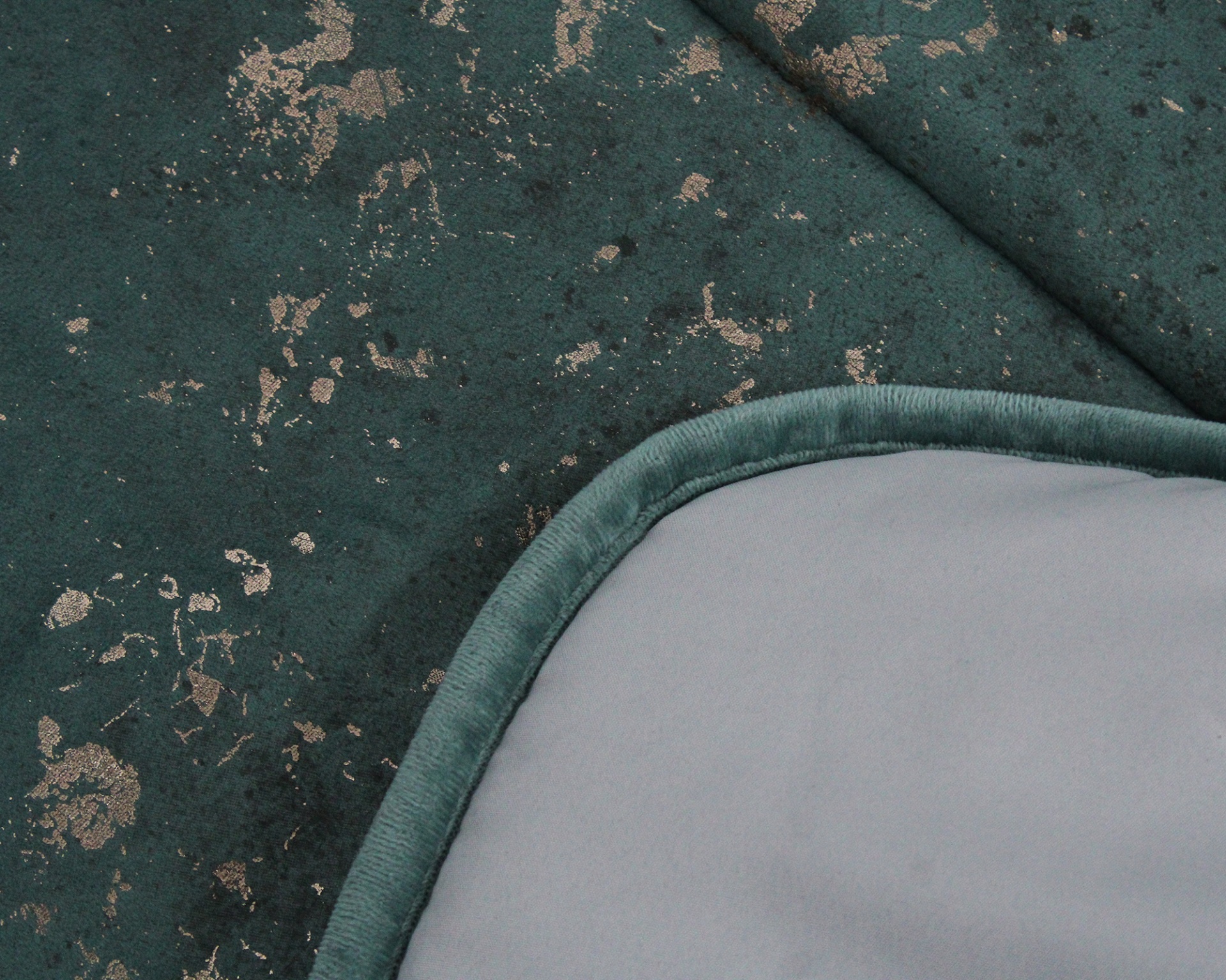 Tecido verde com padrão dourado e textura aveludada com borda e superfície cinzenta