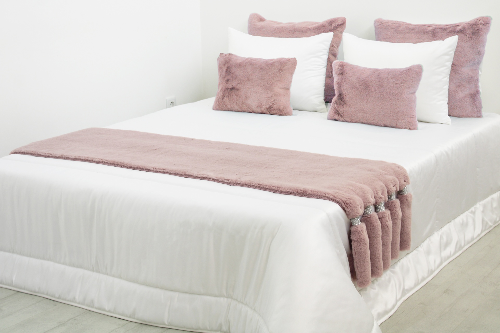 Cama branca com mantas e almofadas rosa peludas