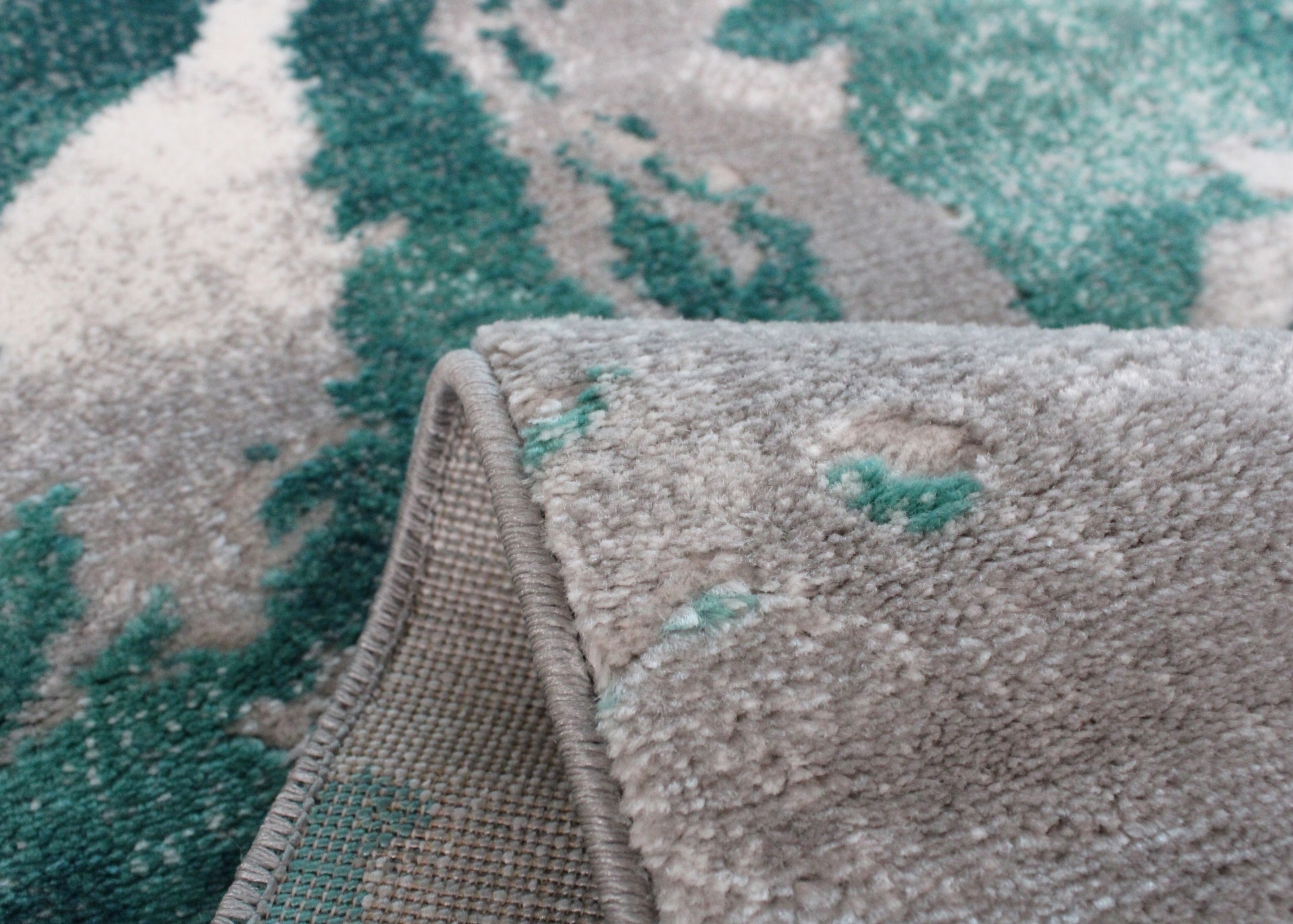 Tapete cinza e verde água com padrão abstrato e dobra mostrando o verso