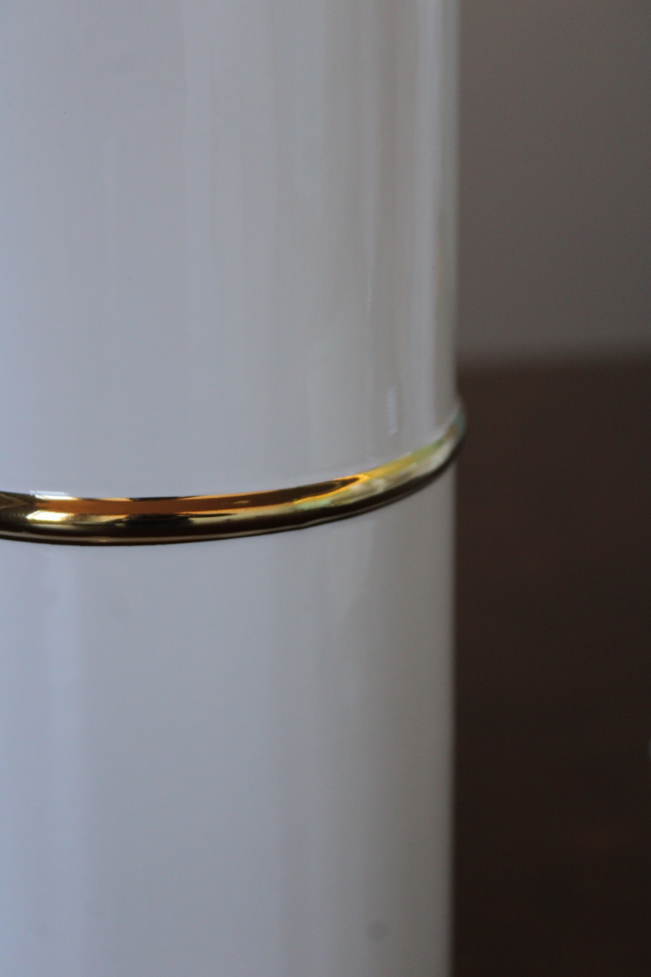 Recipiente branco com faixa dourada e superfície brilhante